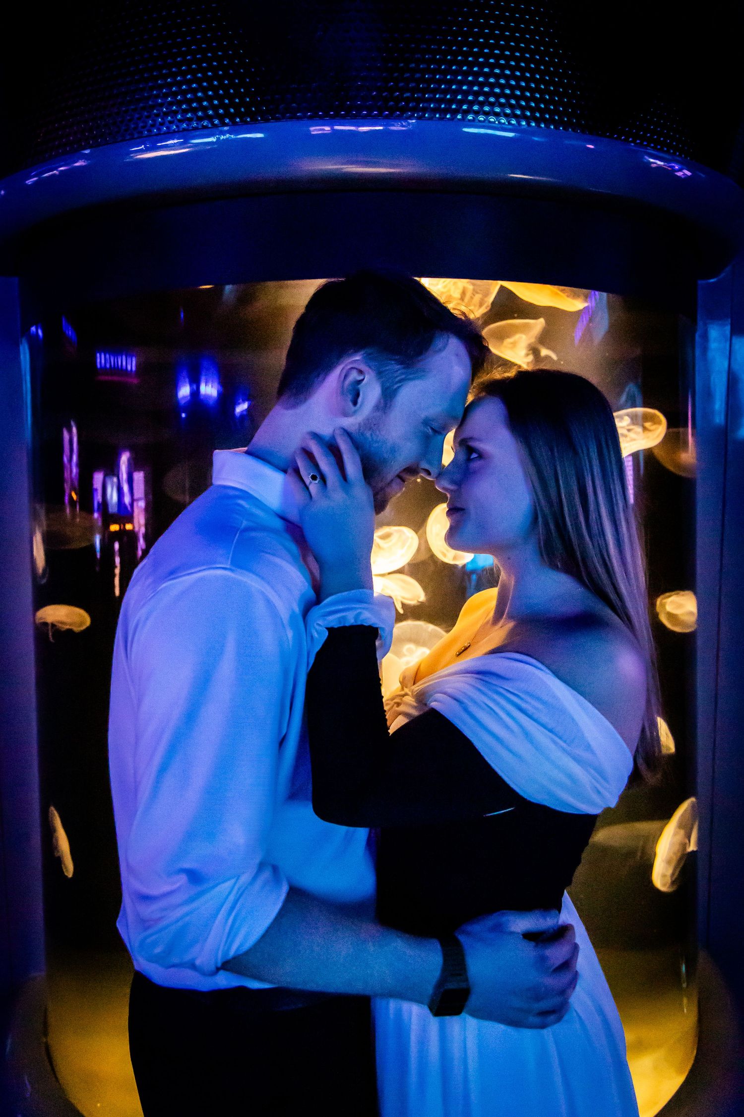 A couple embraces under blue ambient lighting in an intimate nightclub setting.