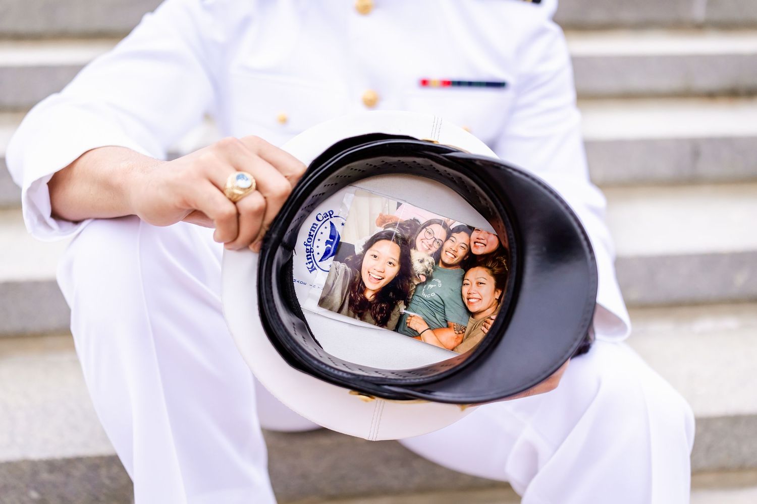 Officer in white uniform holding cover displaying a group photo reflection.