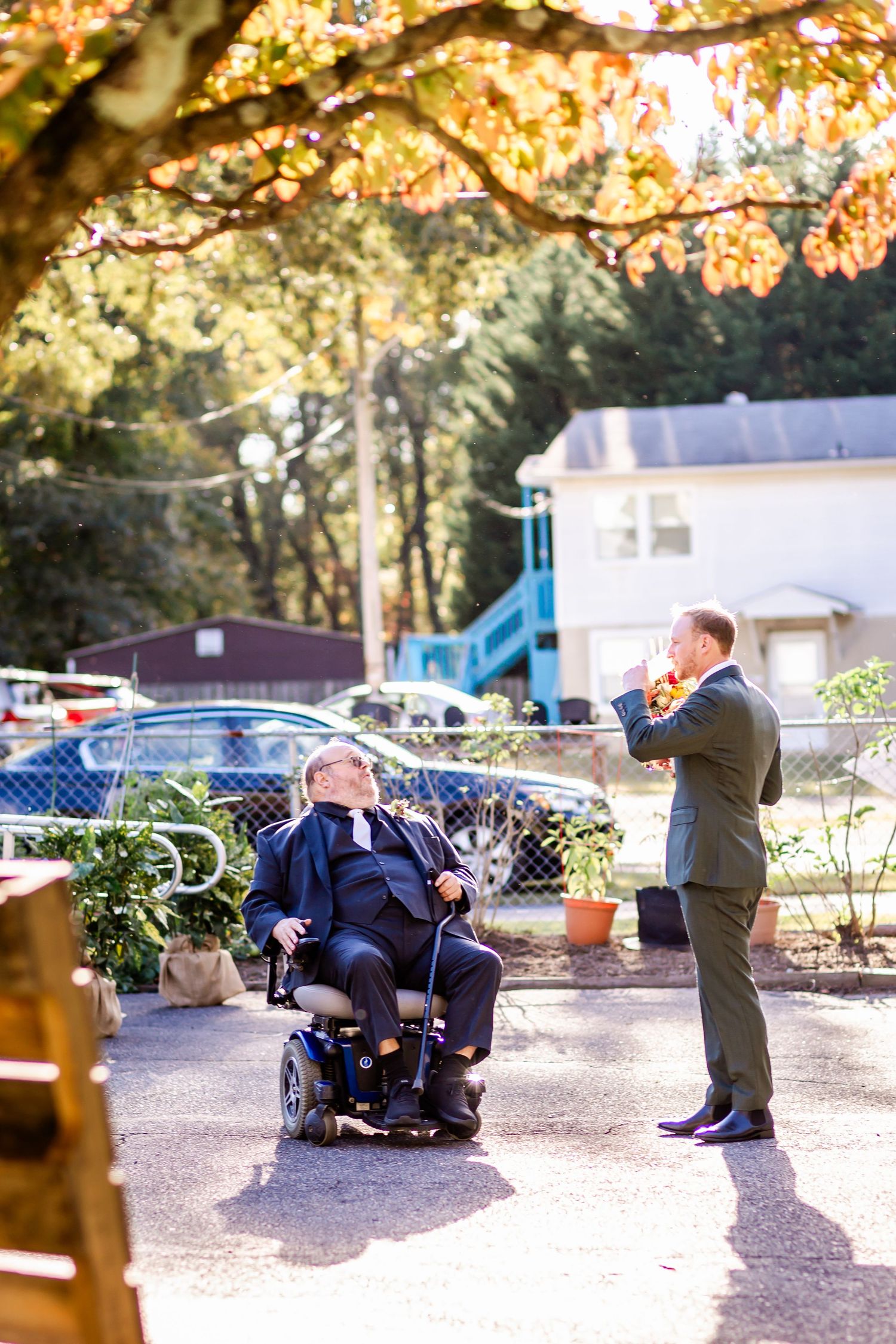A violinist performs outdoors for a guest in a wheelchair during an autumn day.