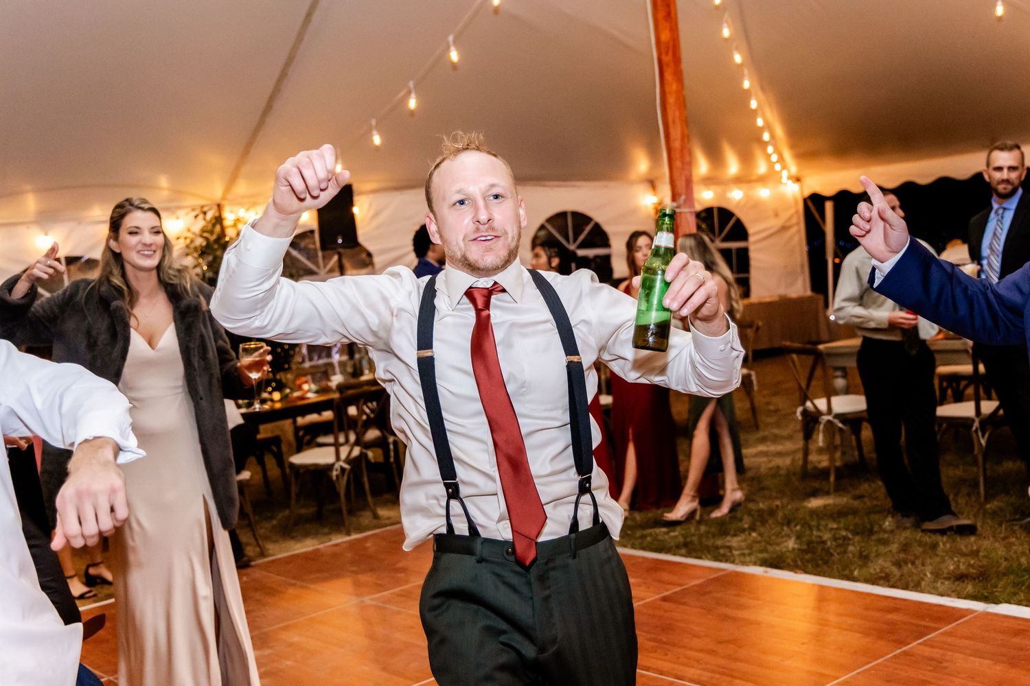 Wedding reception party with guests dancing and celebrating on wooden dance floor.