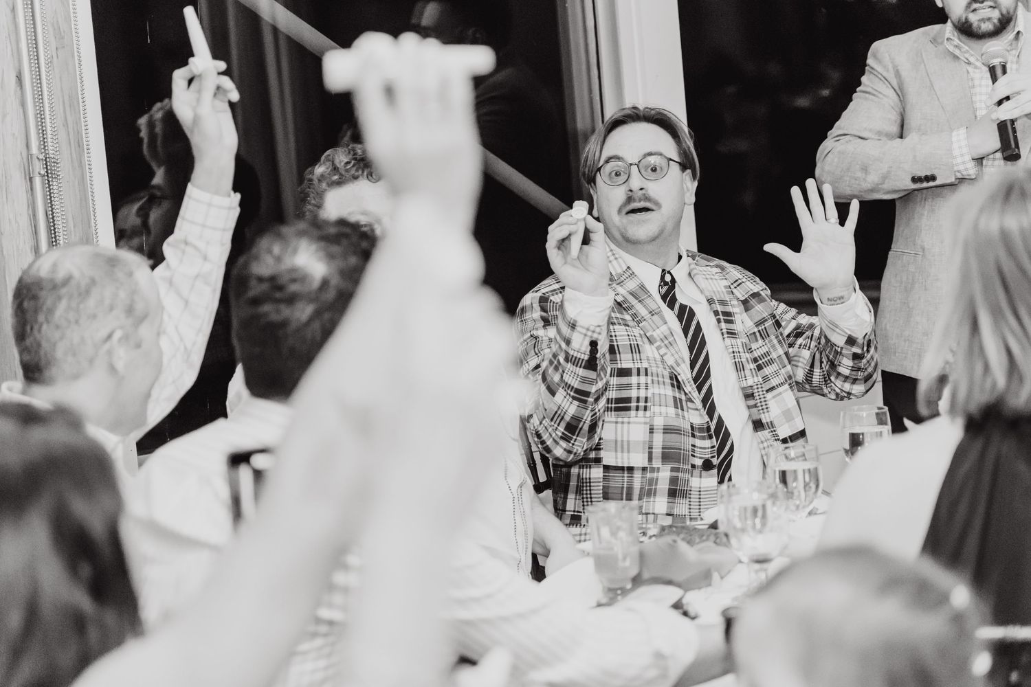 Vintage black and white photo showing an animated party scene with people gesturing enthusiastically at a social gathering.