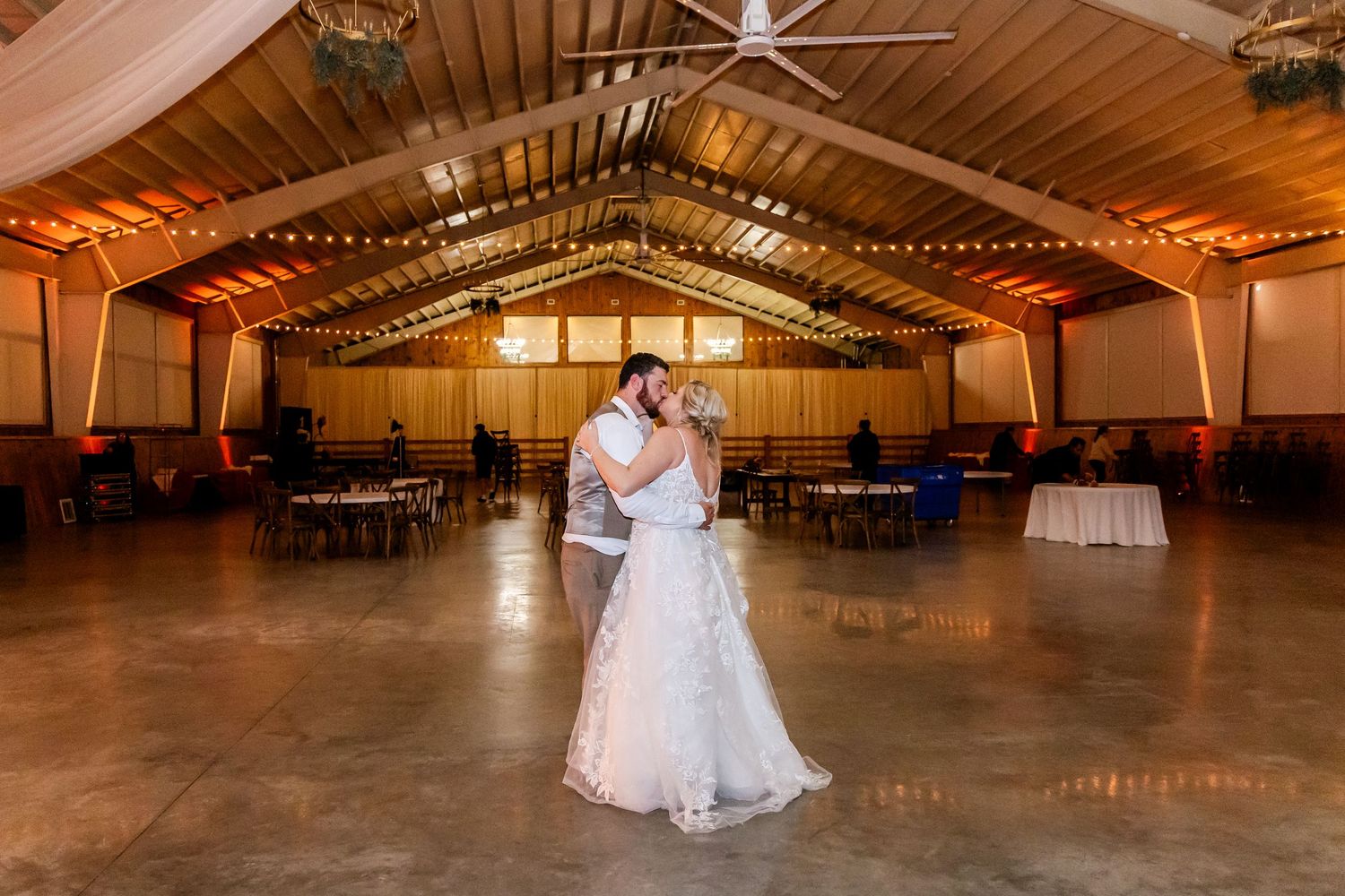 Couples dancing on a wooden floor in a rustic venue with warm lighting and exposed wooden beams overhead.
