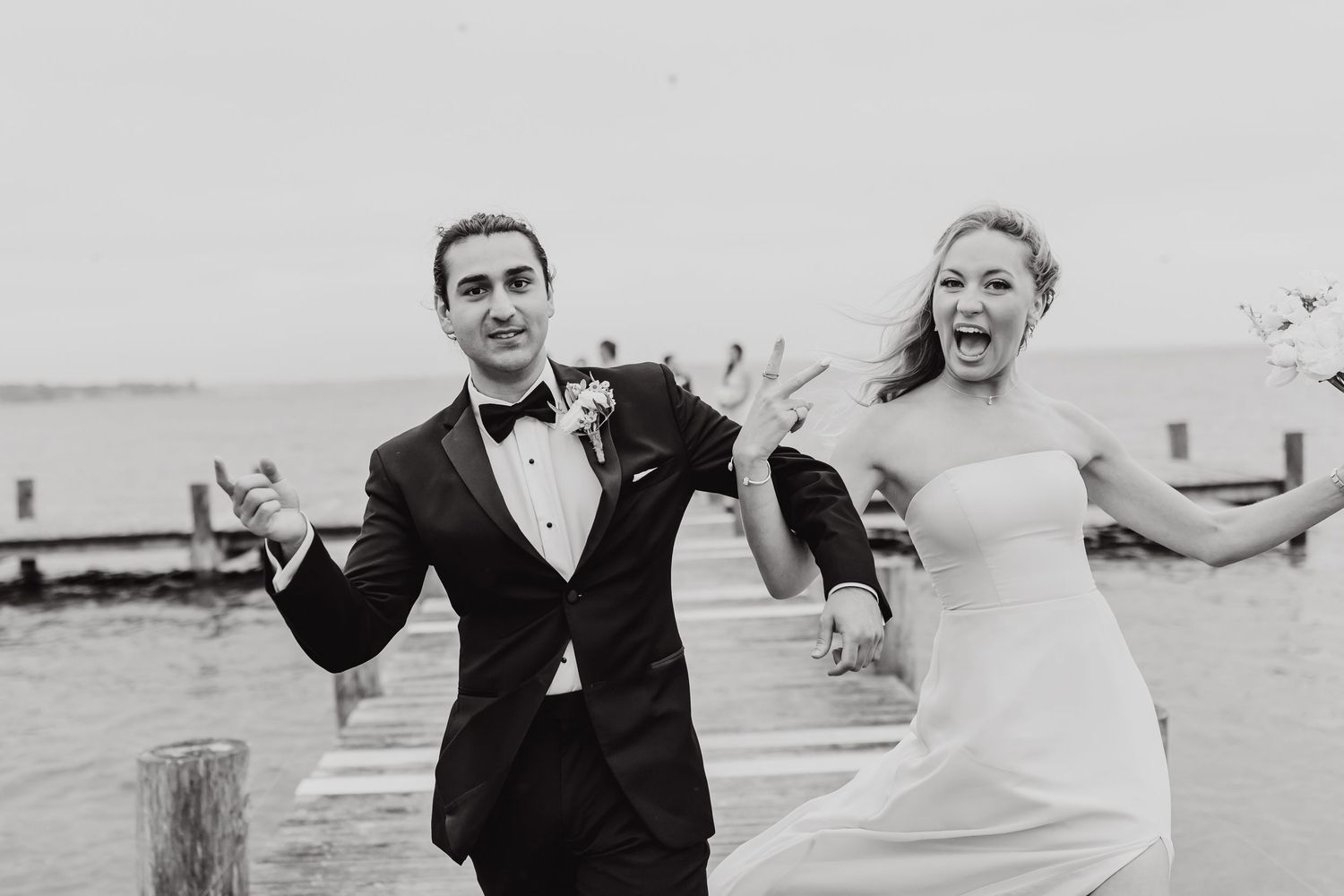 Black and white photo of a couple joyfully dancing together on a beach during their wedding celebration.