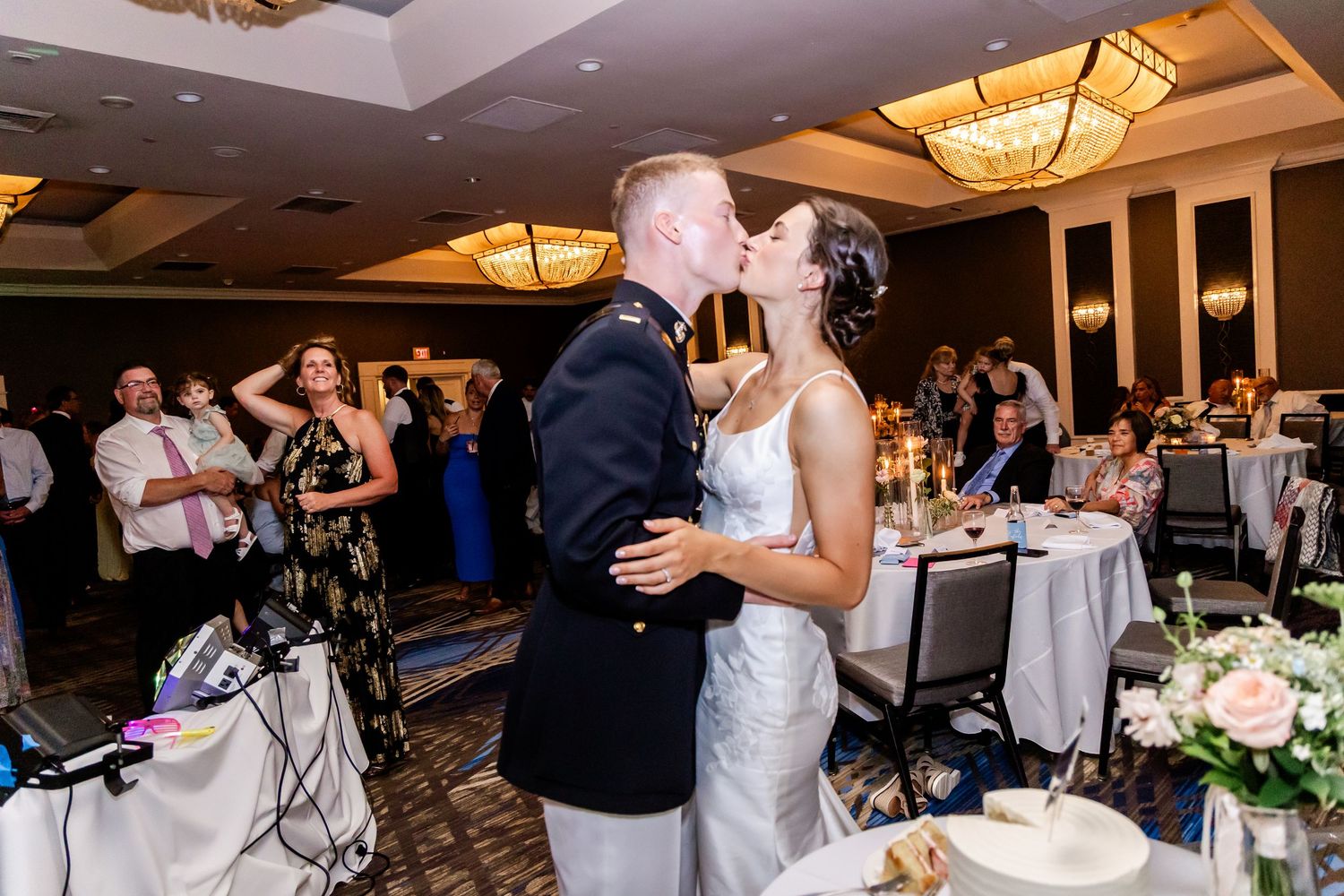 Large group celebrating at wedding reception with dramatic lighting and decorative ceiling fixtures.