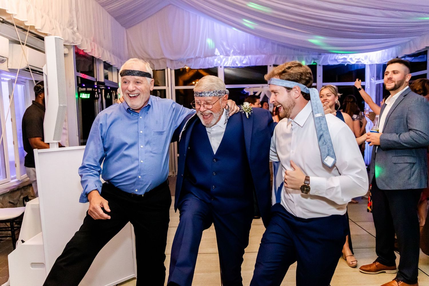 Three guests share laughs and dance moves at an evening wedding reception.