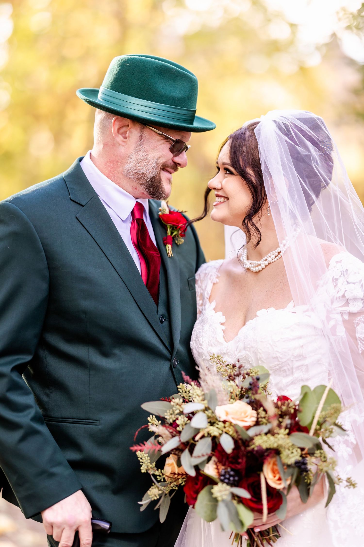 Intimate wedding portrait showing couple in formal attire with autumn foliage backdrop.