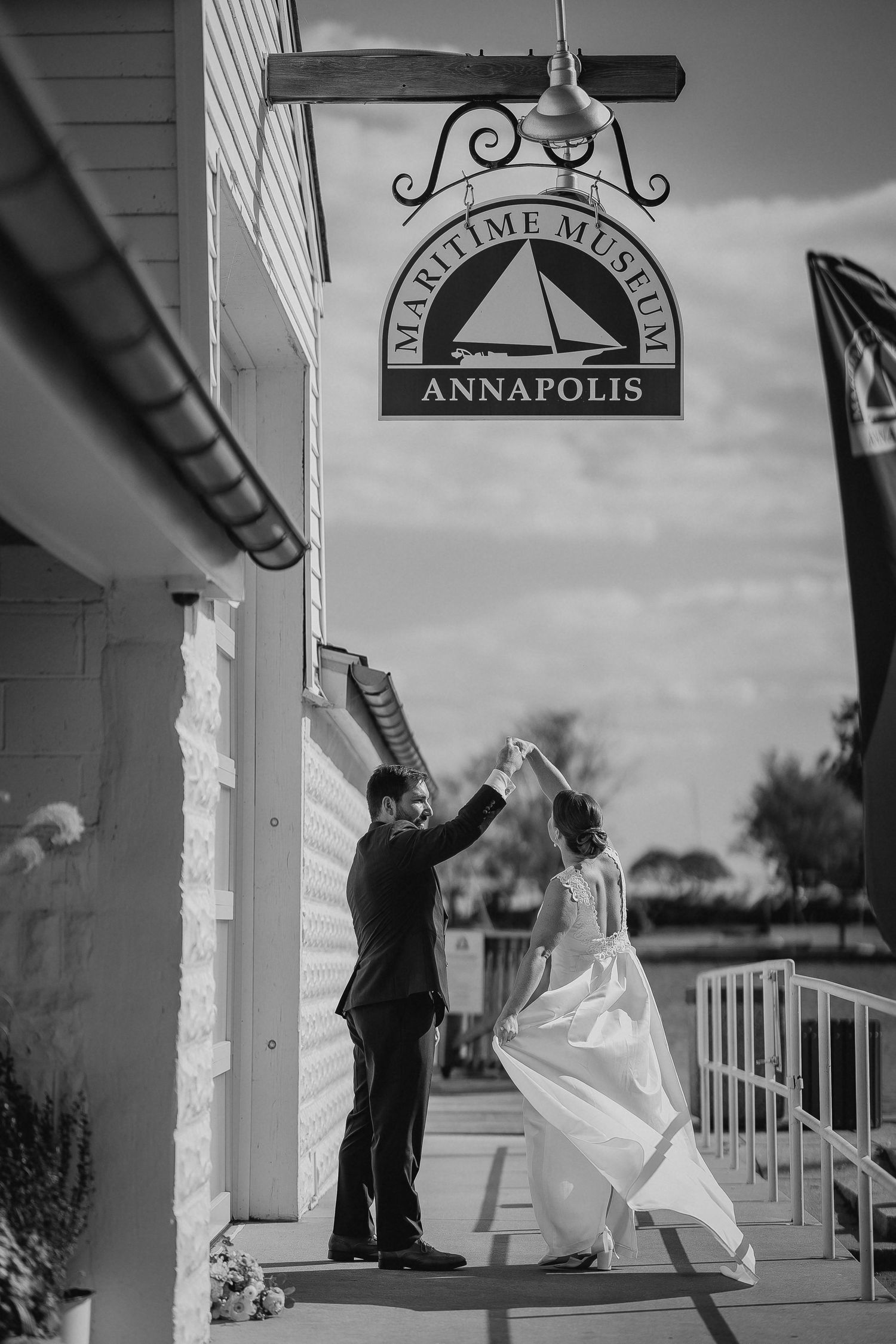 Bride and groom dancing outside the Maritime Museum Annapolis in a black and white wedding photo.