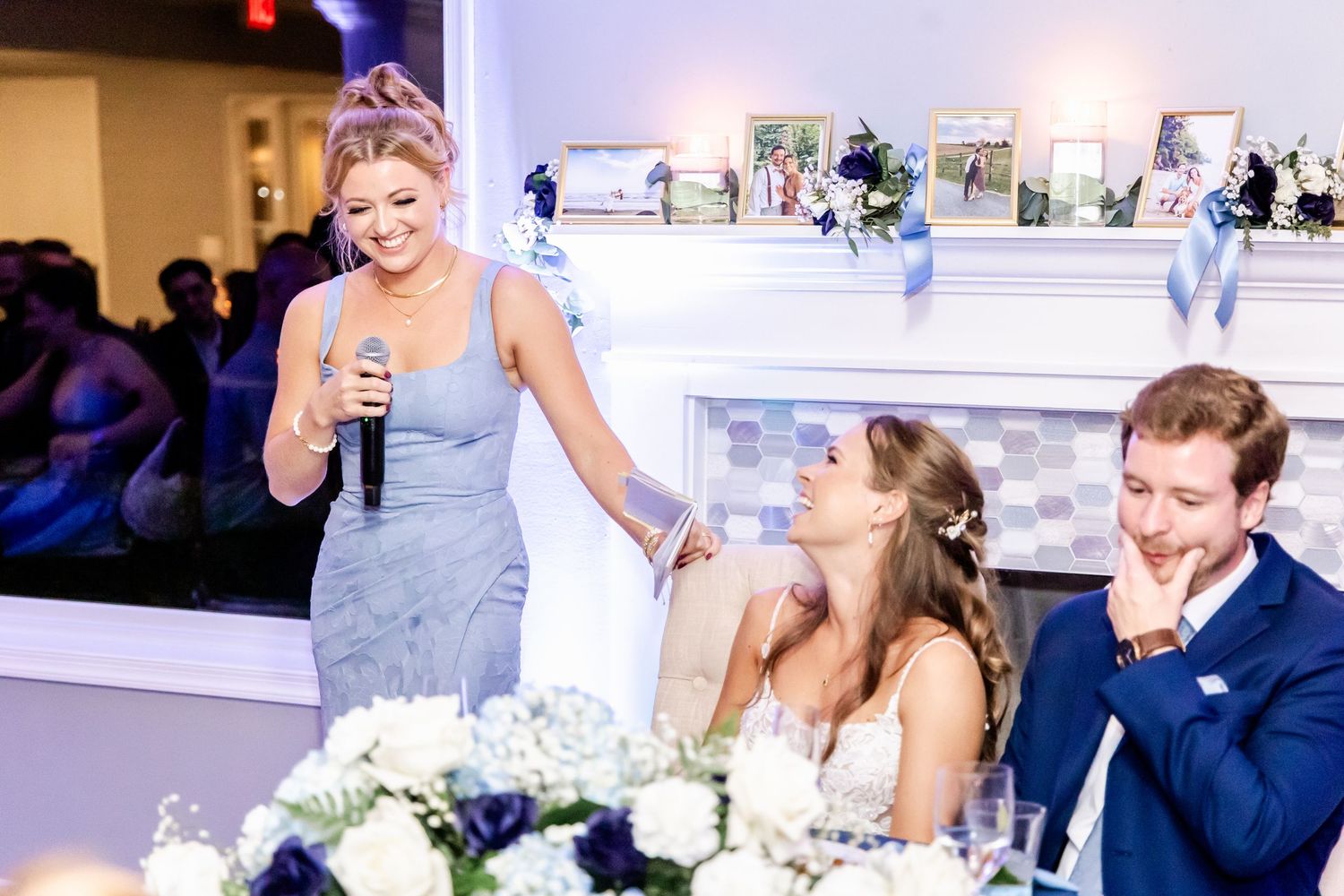 Wedding reception speech with bridesmaid in gray dress at decorated venue.