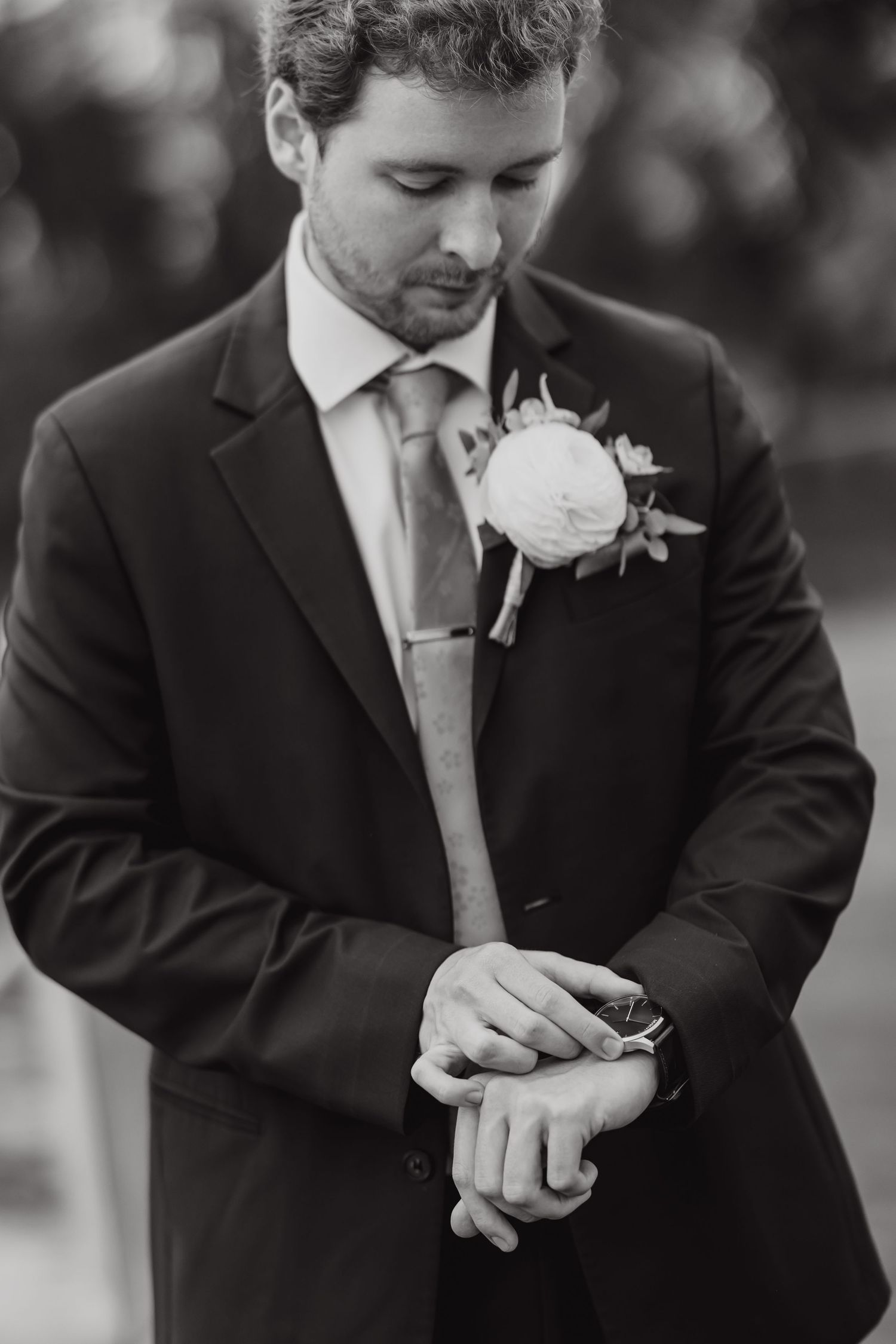Black and white series of groom adjusting boutonniere and cufflinks before ceremony.