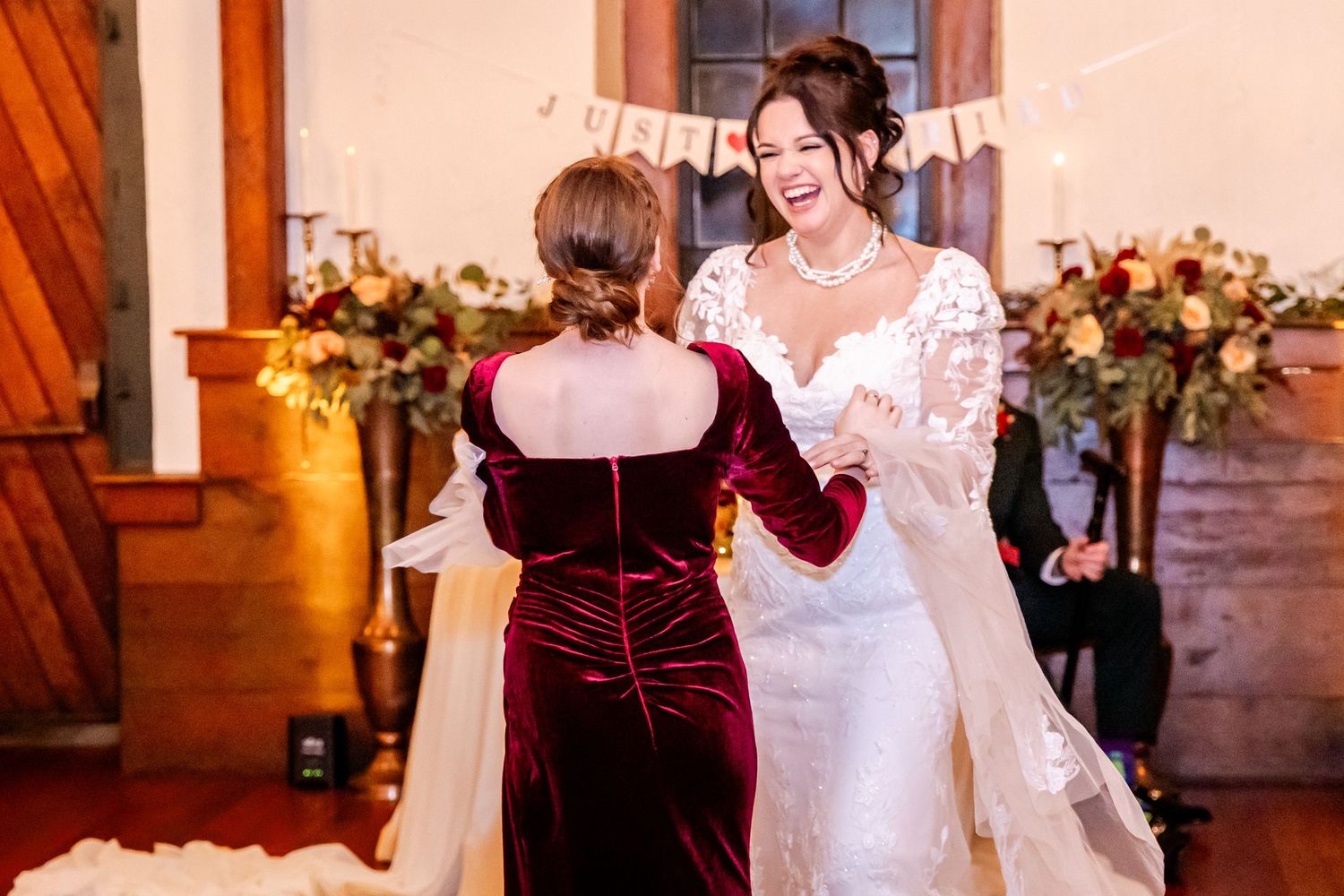 Wedding guests dancing and celebrating on a wooden dance floor at an indoor reception.