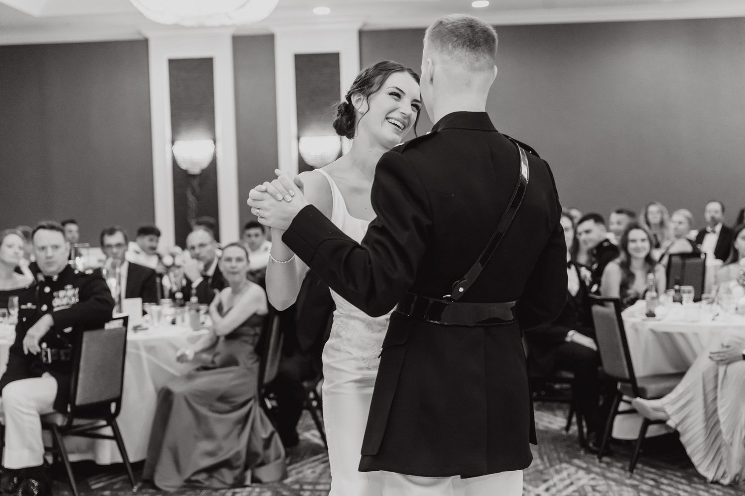 Wedding reception guests celebrate and dance in a modern indoor venue space.