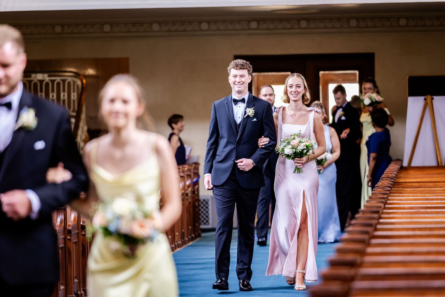 Wedding party members walking down a grand staircase in formal attire during the ceremony.