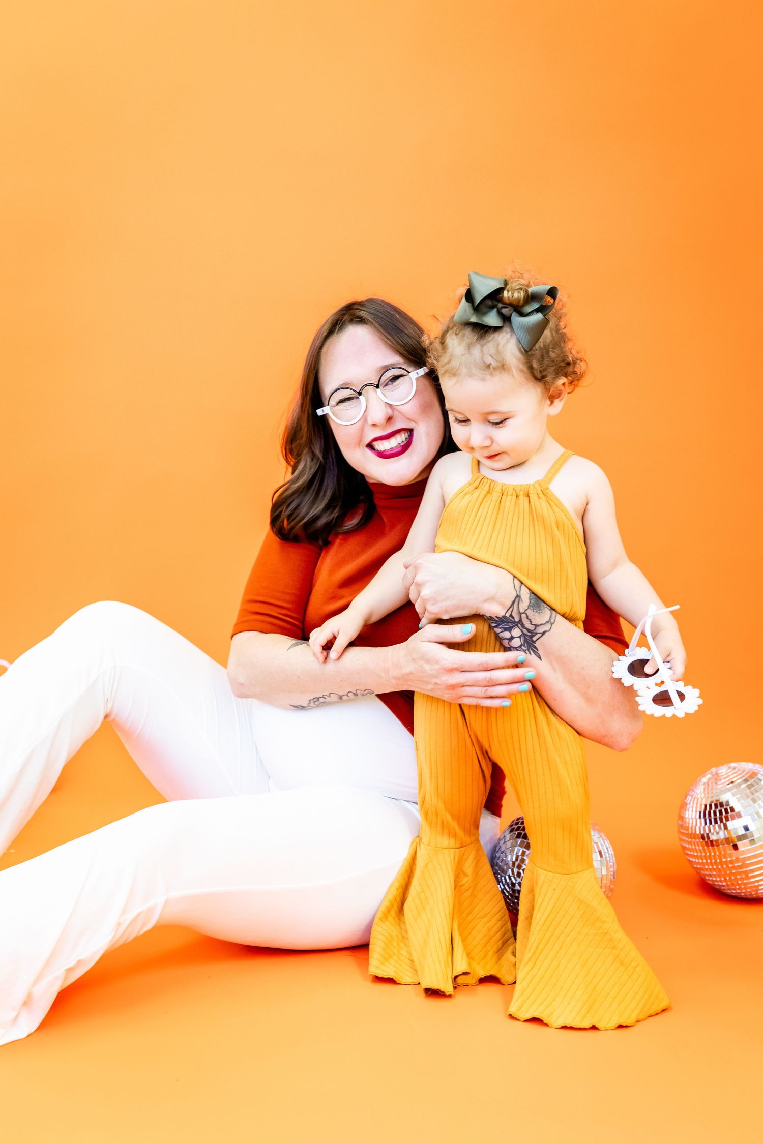 Family in orange and yellow outfits playing on bright orange background.