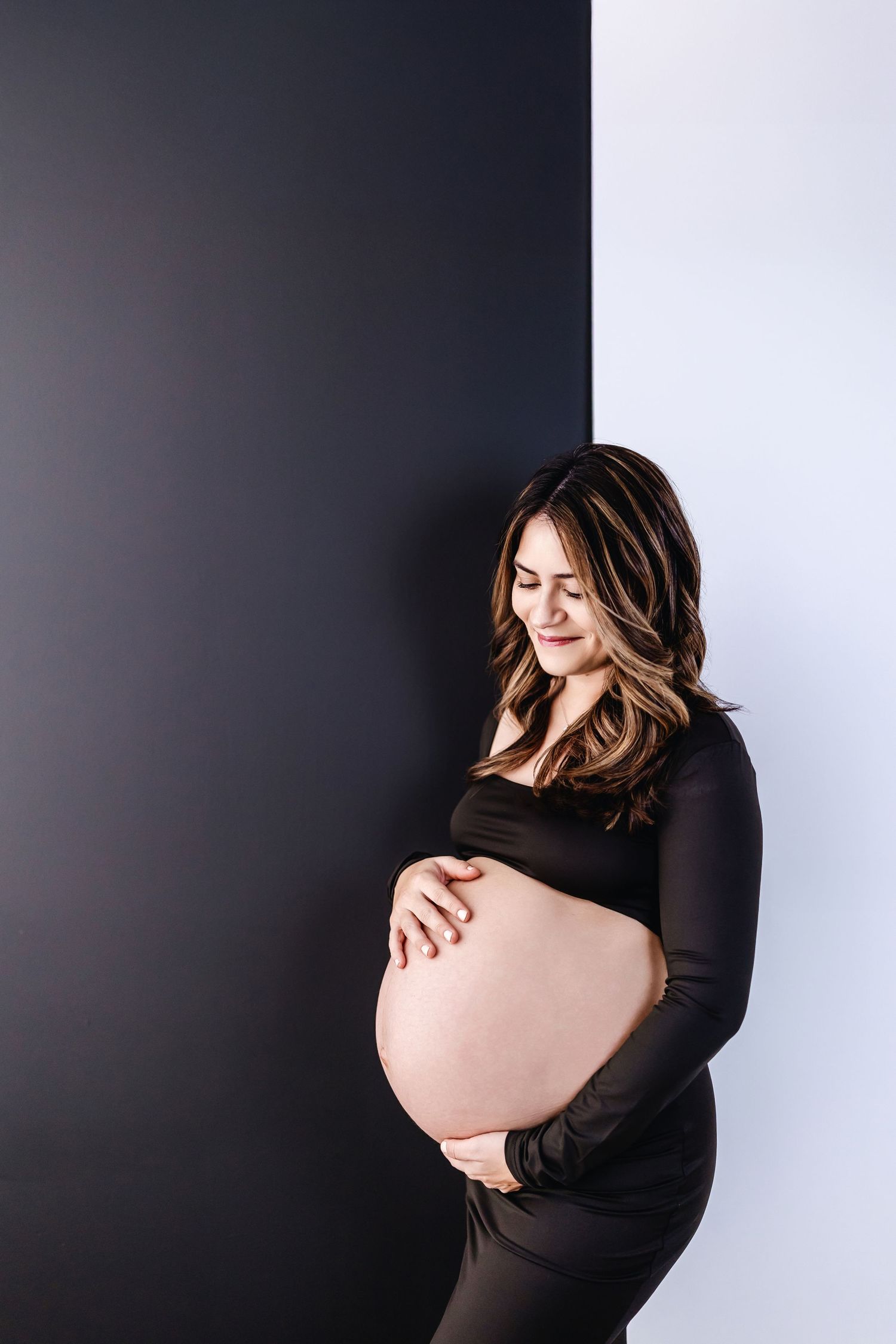 Artistic maternity photos showing pregnant belly silhouette against dark and light backdrop.
