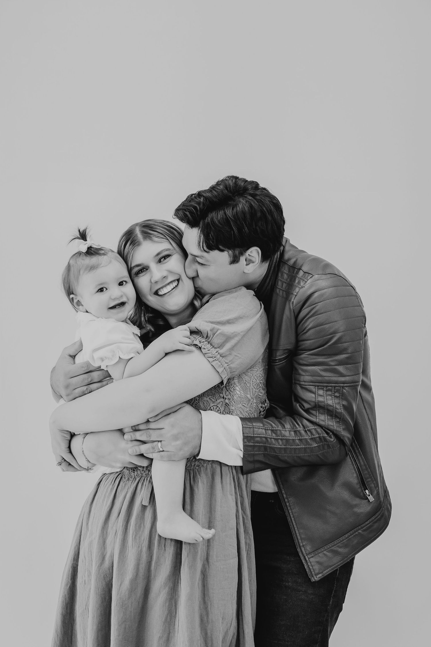 Black and white family portraits showing loving embraces and joyful moments together.