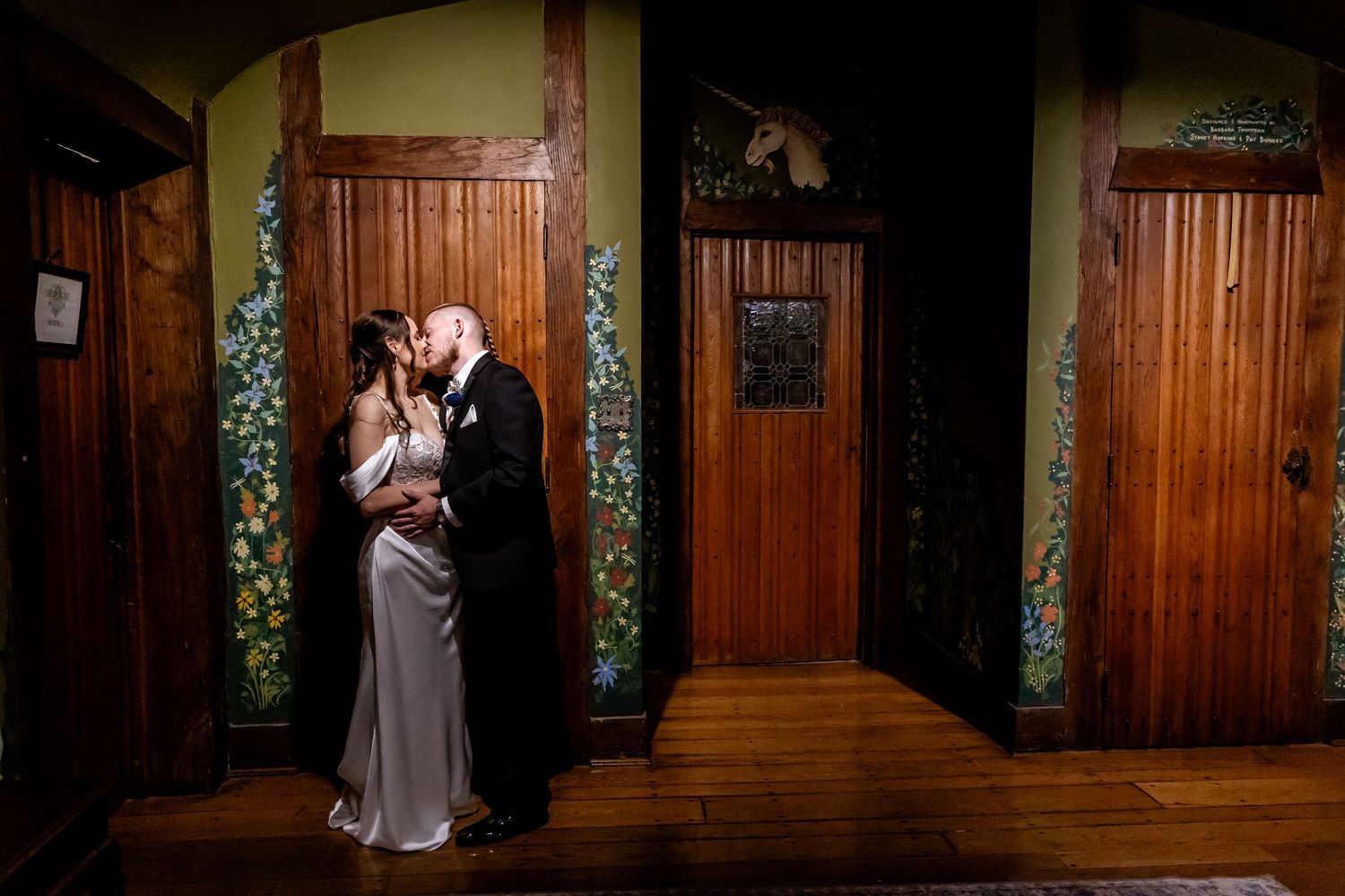 A romantic wedding moment captured in a church corridor with dark wood paneling and soft lighting.