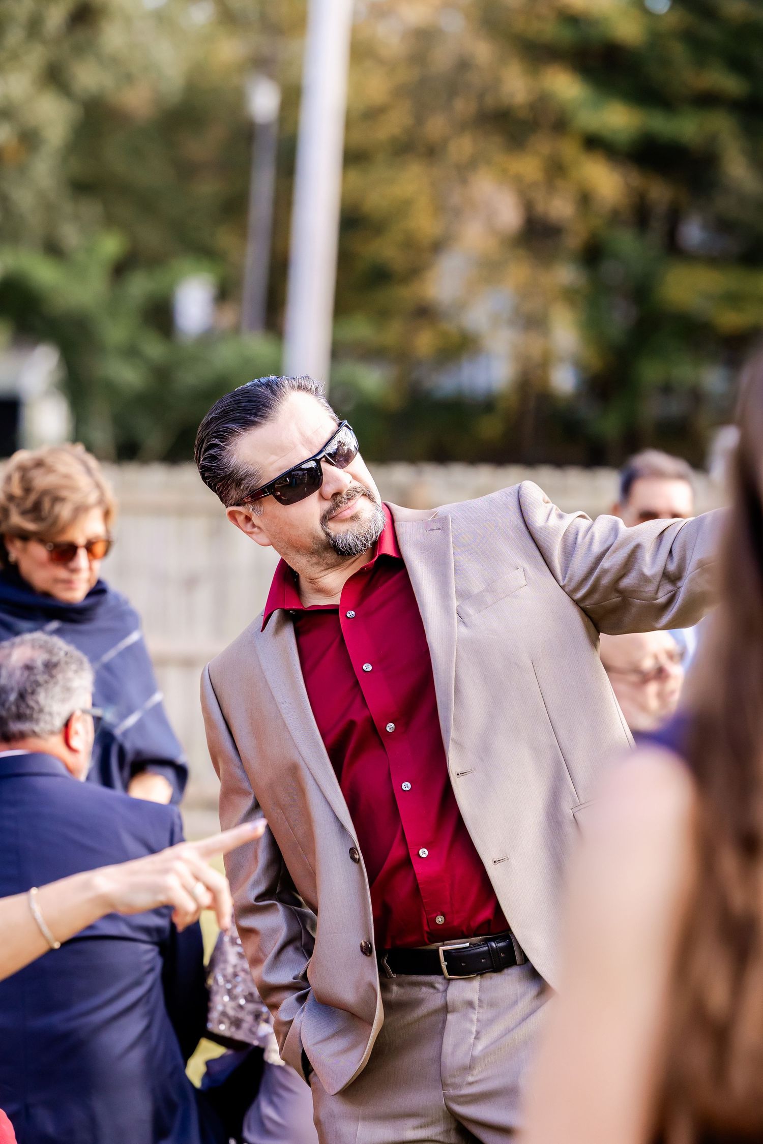 Wedding guests mingle outdoors during a casual daytime reception.