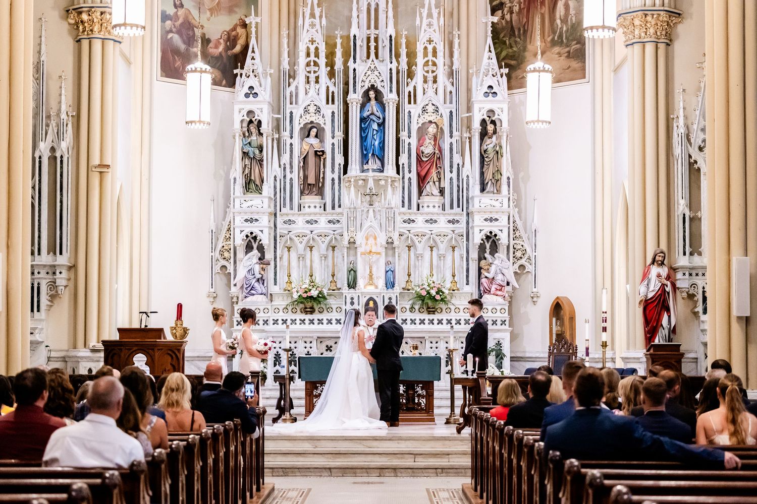 A traditional church wedding ceremony with ornate gothic architecture and stained glass windows in the background.