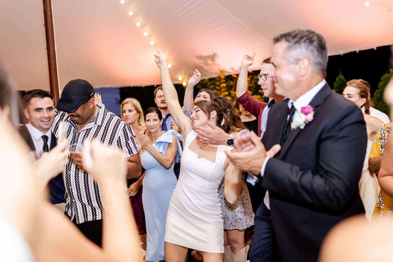 Wedding guests dancing and celebrating on a lively dance floor at an evening reception.