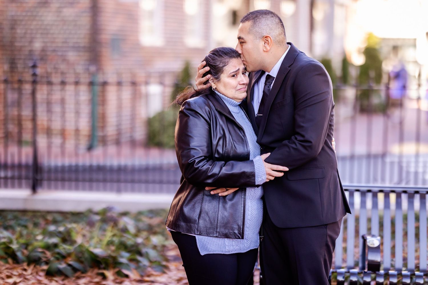 Sweet moment shared between couple in formal wear outside brick building.