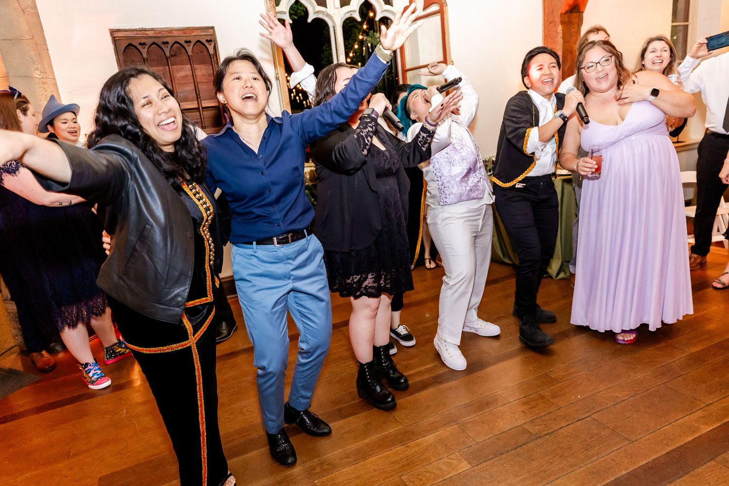 Wedding reception guests dancing energetically on a hardwood dance floor.
