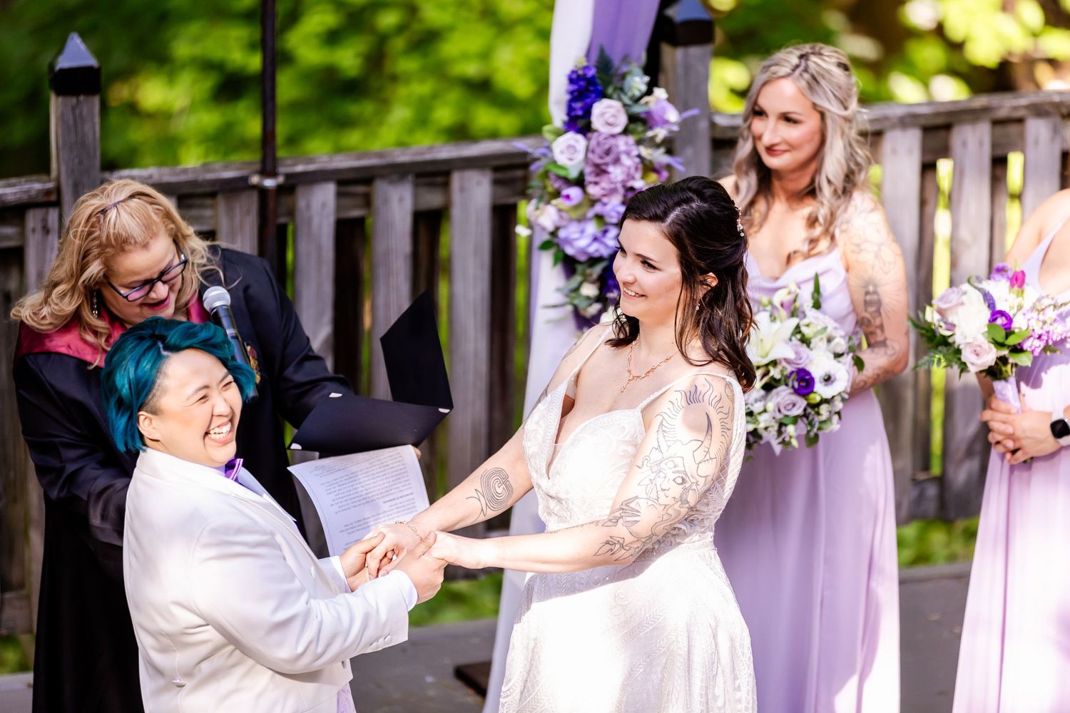 An intimate wedding ceremony moment captured outdoors with purple and white decorations.