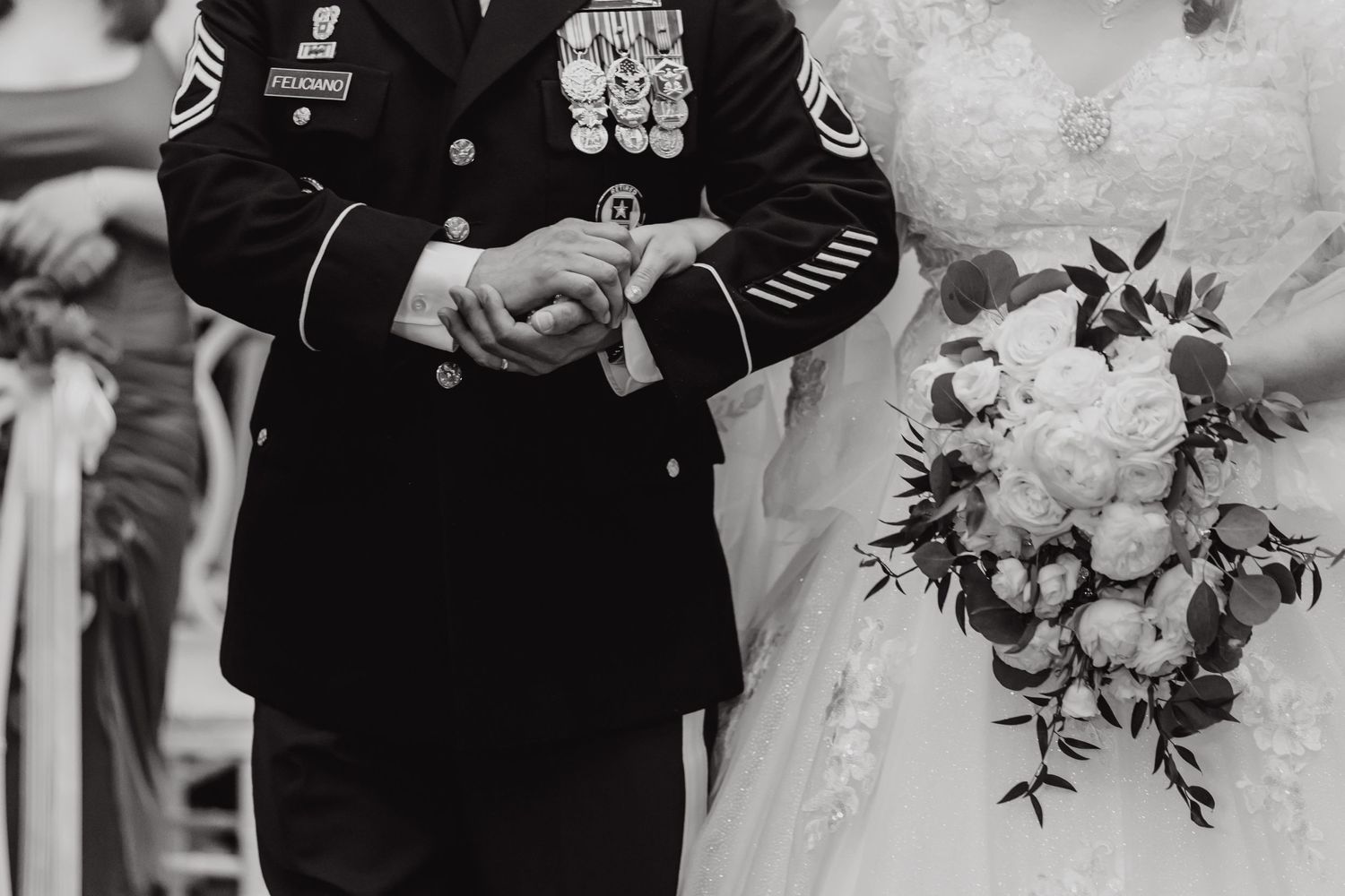Black and white photo of military officer and bride holding hands during wedding ceremony.