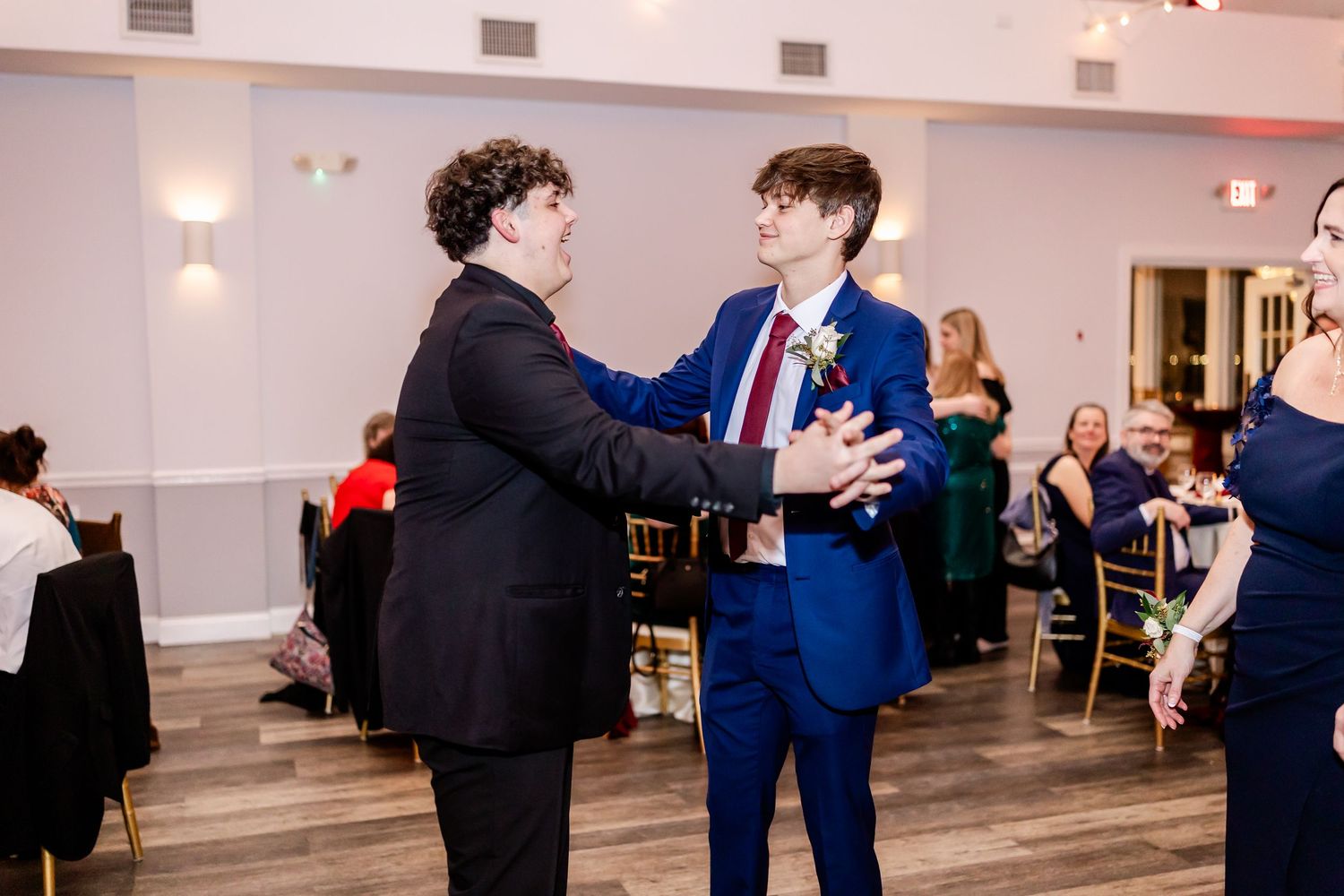 Guests dancing and socializing at a wedding reception in a modern venue with hardwood floors.