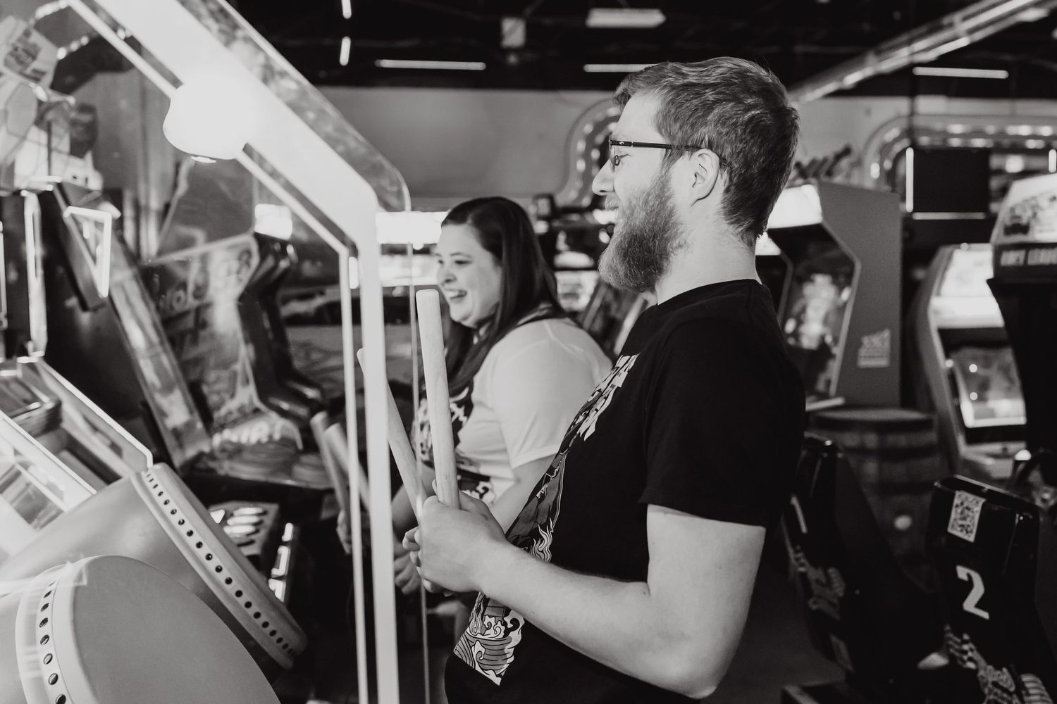 People enjoying classic arcade games in a retro gaming arcade with vintage cabinets in black and white.