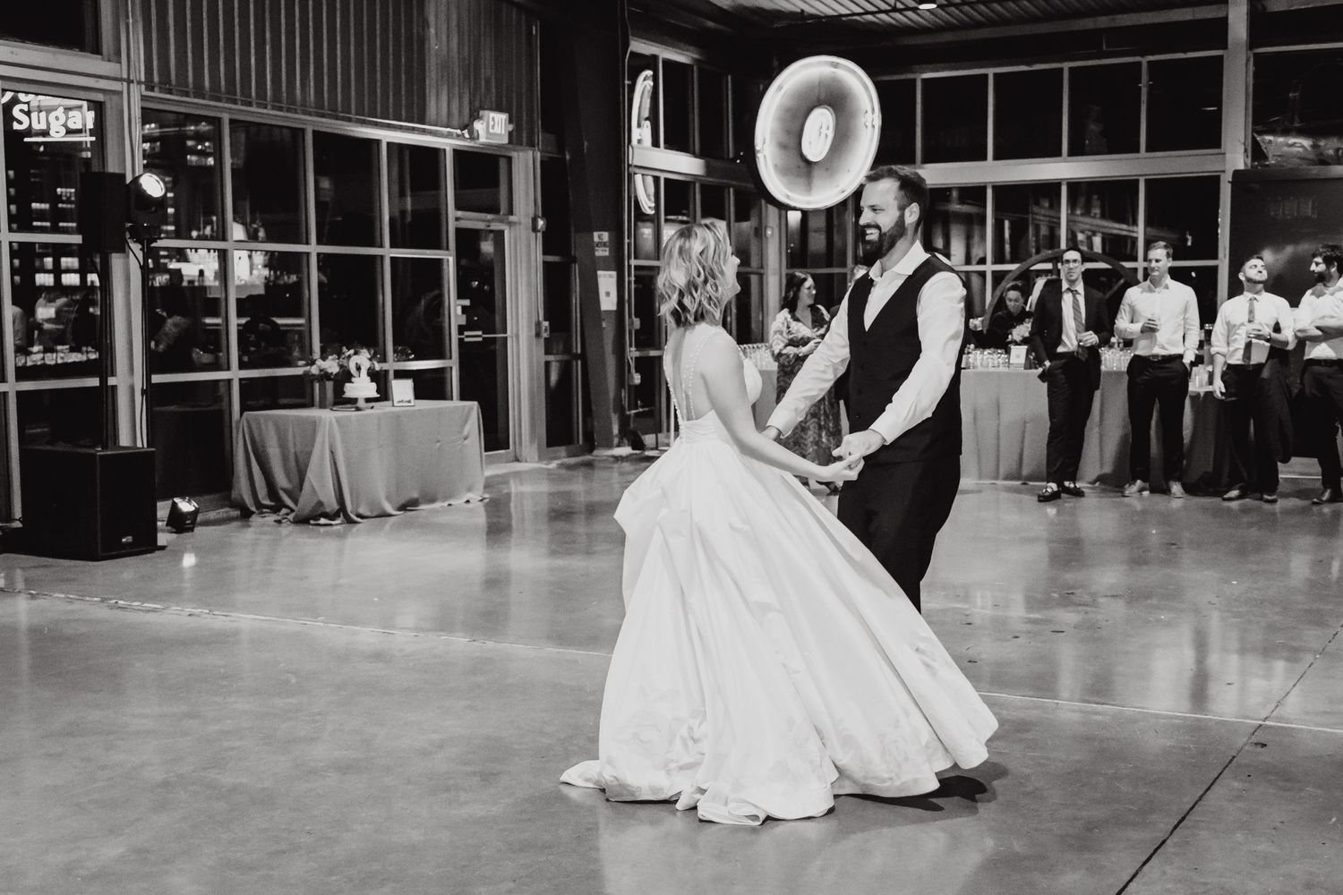 Black and white photo of a wedding couple dancing at their reception in a spacious venue.