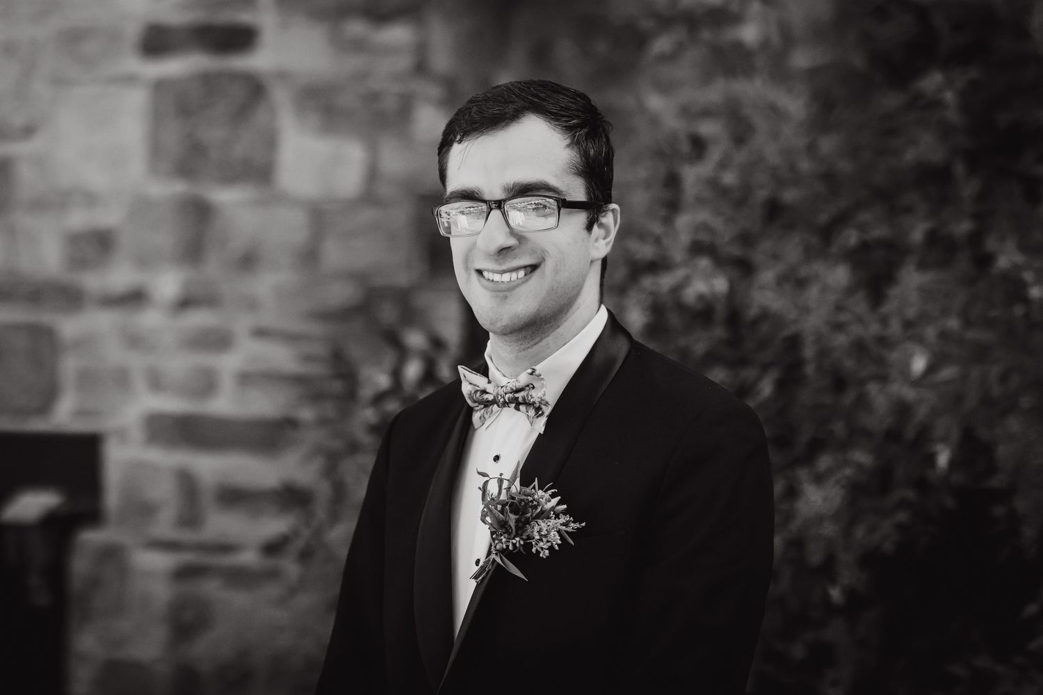 Classic black and white portrait of groom wearing bow tie and glasses.