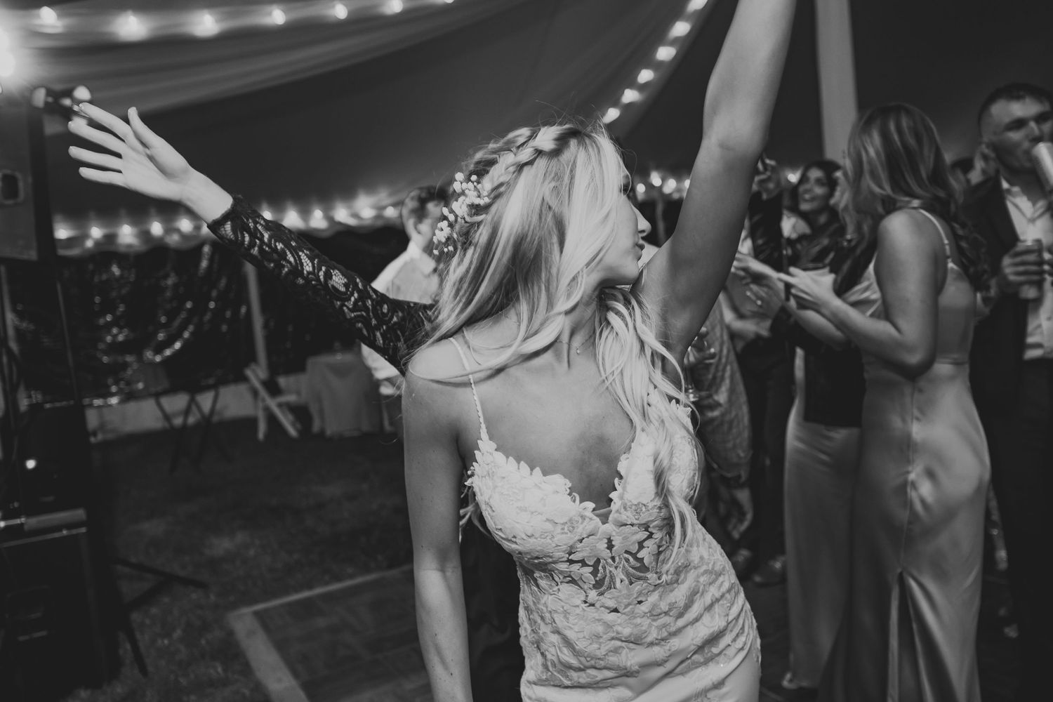 Black and white photo of joyful dancing at a wedding reception with guests celebrating on the dance floor.