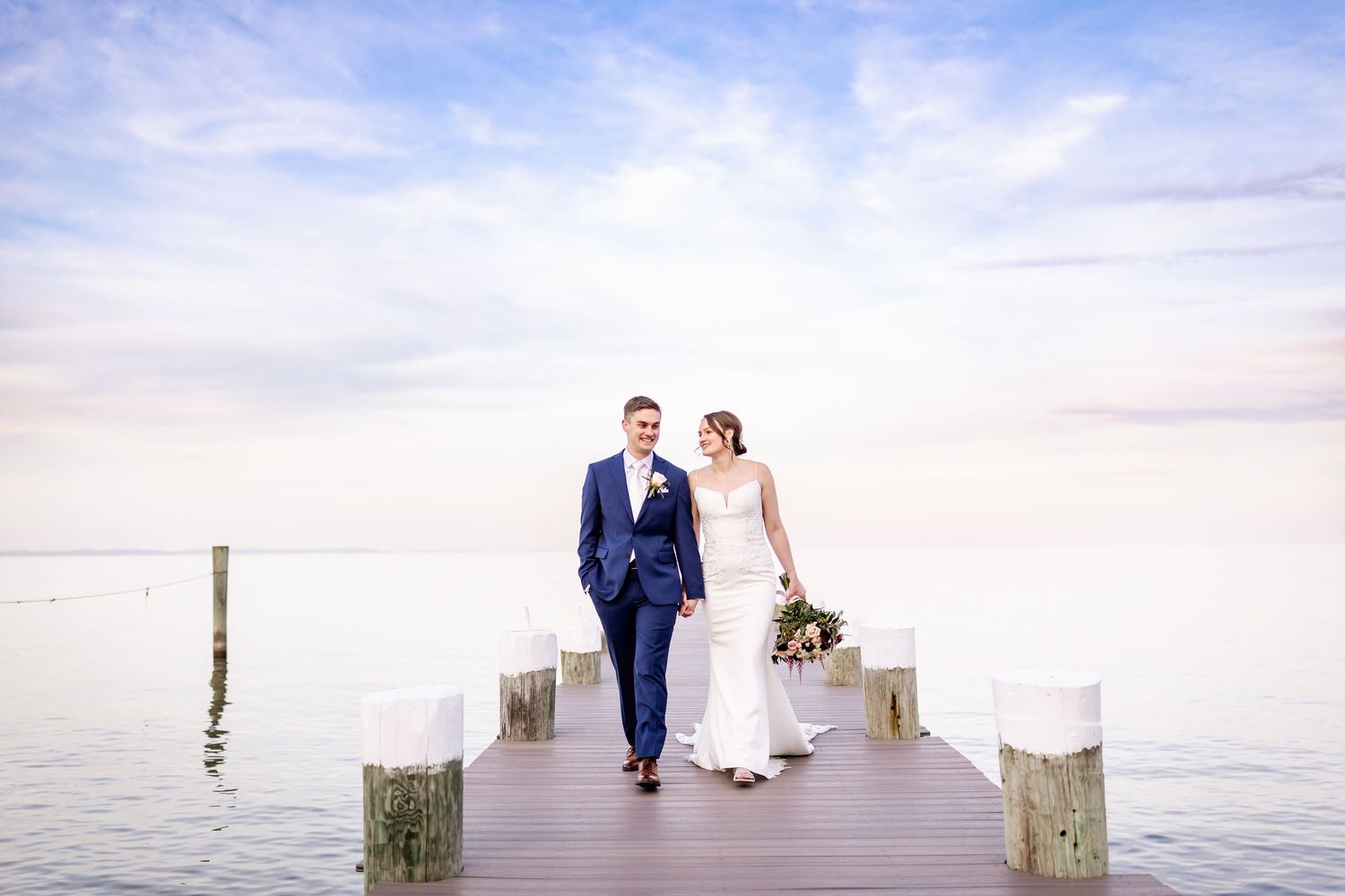 A couple shares a romantic moment on a dock by the water during sunset.