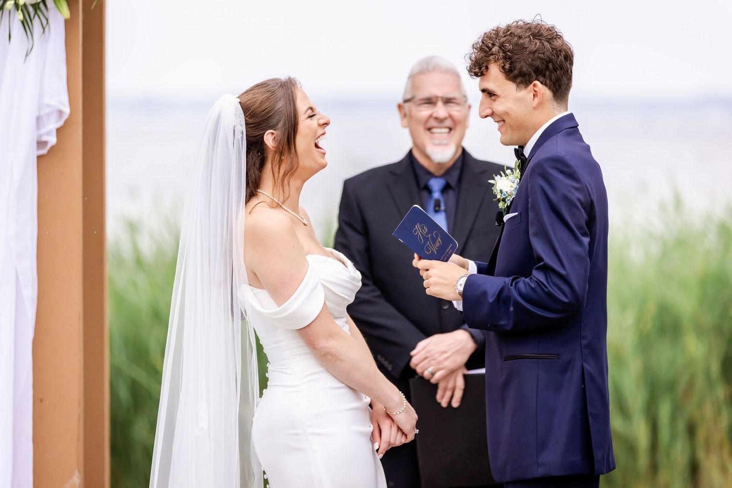 A wedding couple embraces in front of a scenic outdoor backdrop.