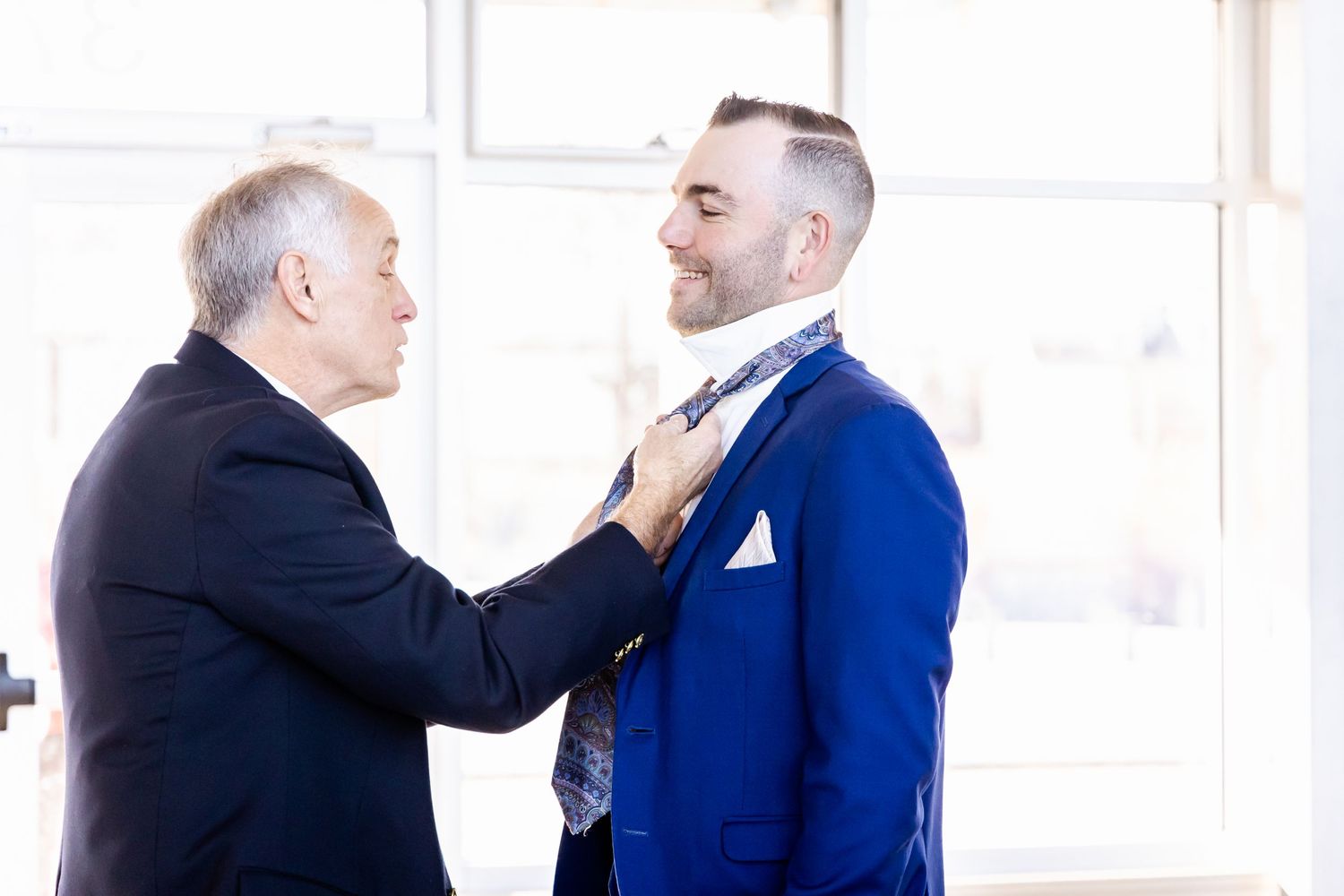 A formal moment of adjusting a blue suit tie before the ceremony.