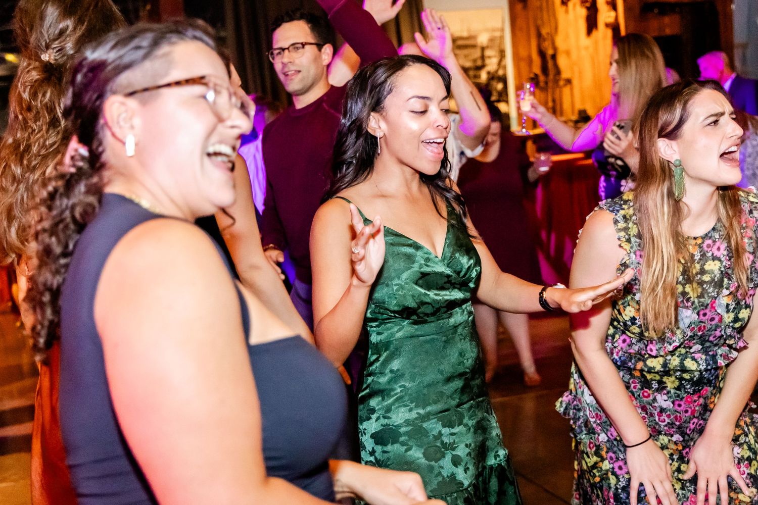 Wedding guests dancing and laughing together at lively reception celebration.