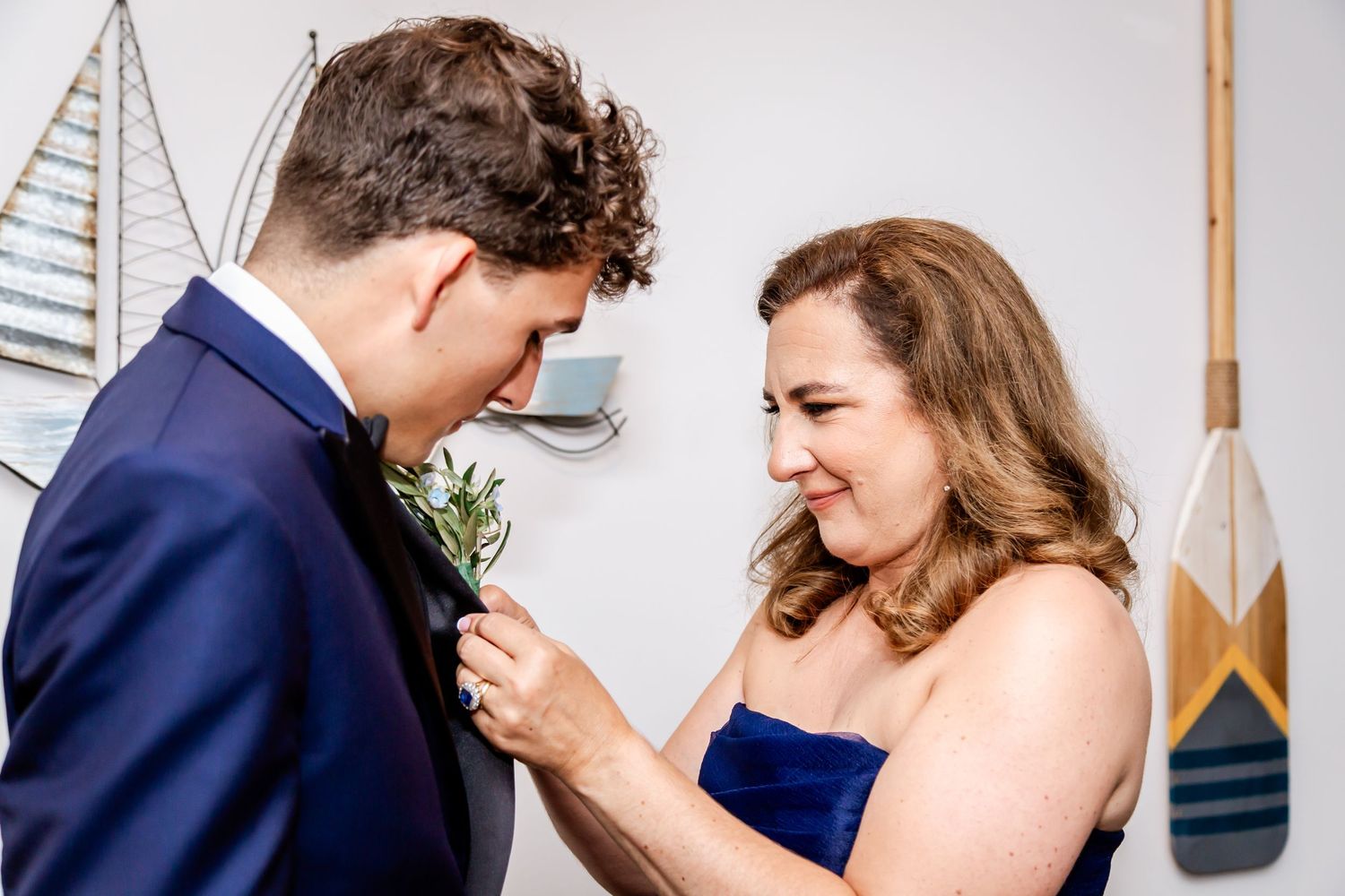 Intimate wedding couple moment captured against white wall with decorative oars.