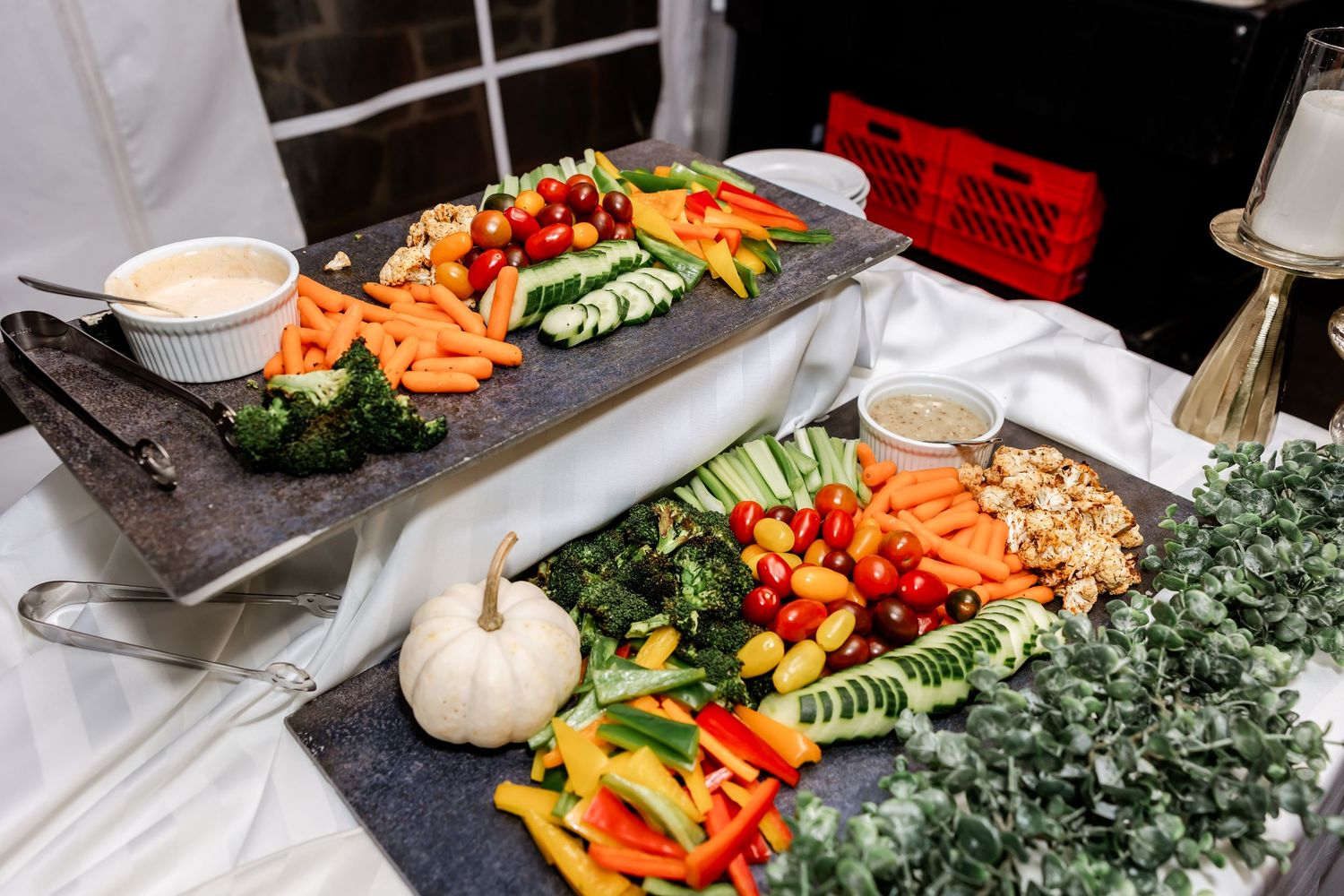 An elegant wedding reception buffet featuring fresh vegetables, fruits and white pumpkin decorations.