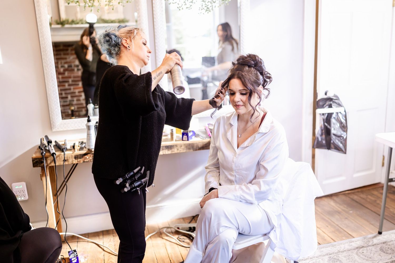Bride getting ready with help from stylists in a bright, modern dressing room.