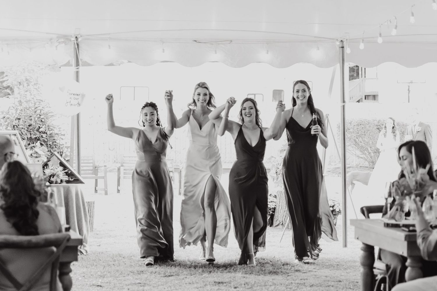 Black and white photo of wedding guests dancing and celebrating at a reception.
