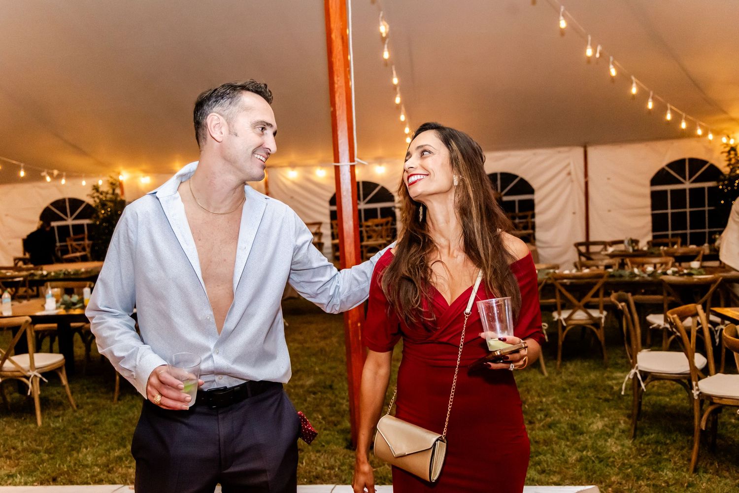 Couples dancing and celebrating at an evening wedding reception under a tent with string lights.