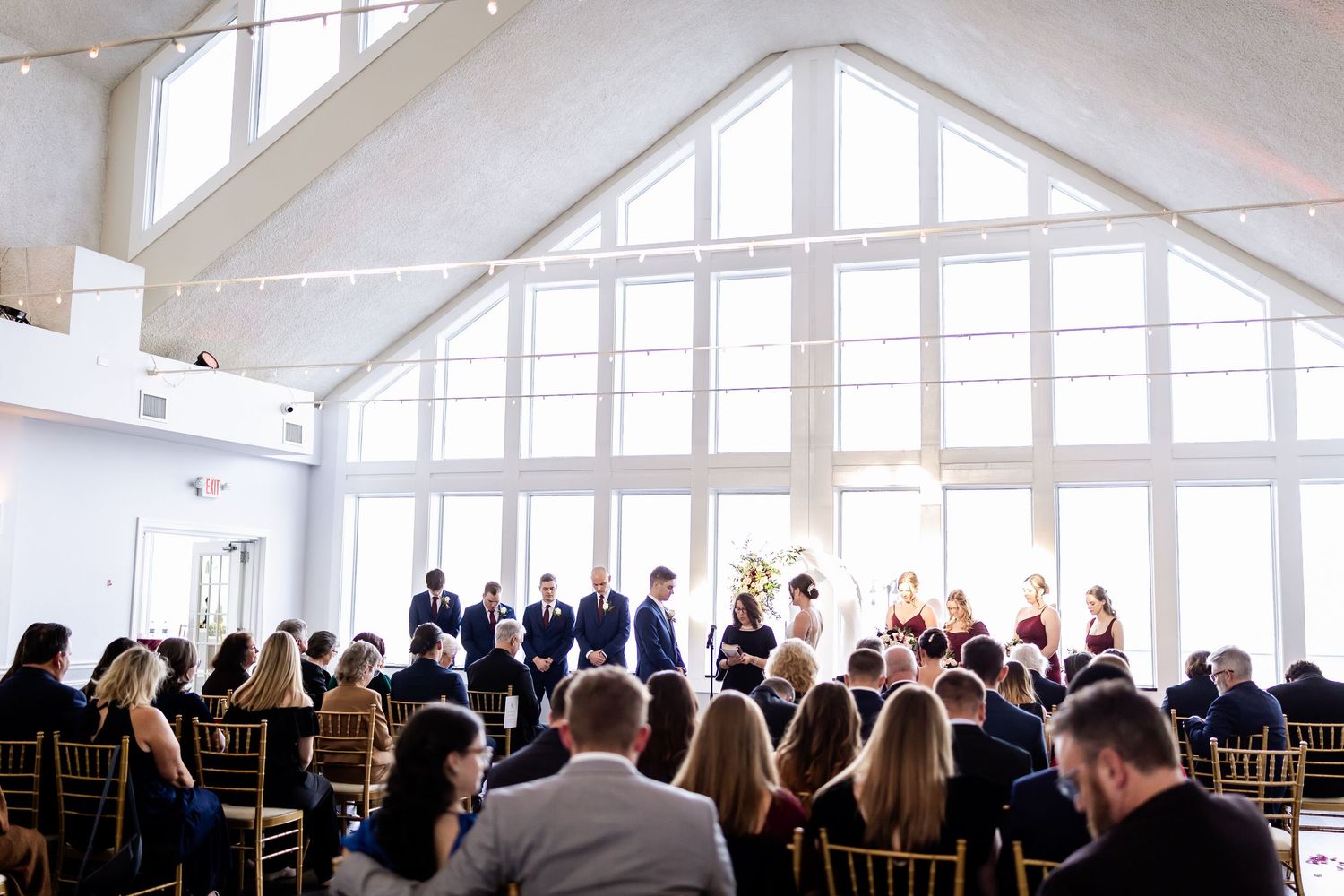Large bright reception venue with vaulted ceiling and rows of chairs set up for a ceremony.