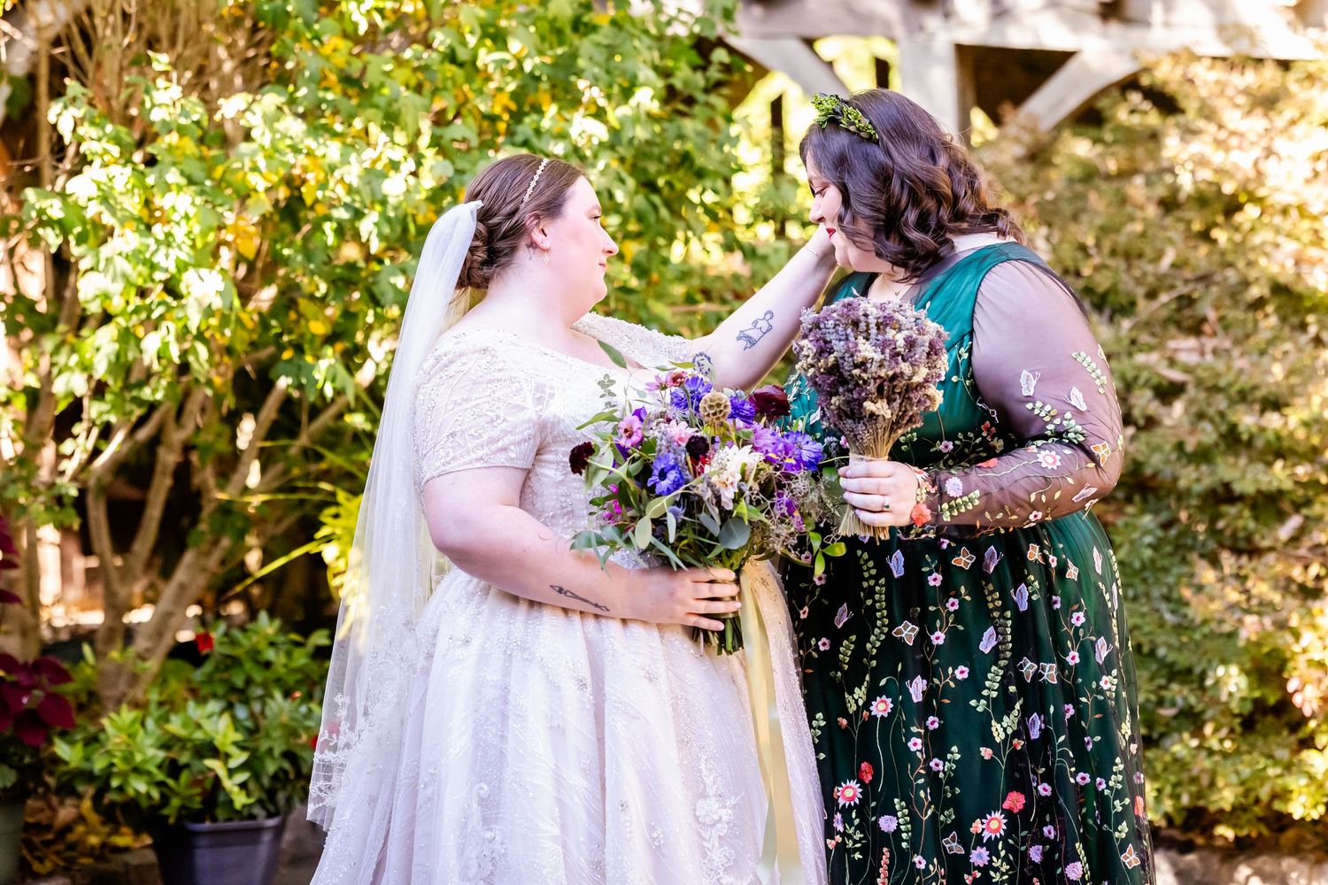 Wedding scene in a garden with bride holding purple bouquet sharing moment with guest.