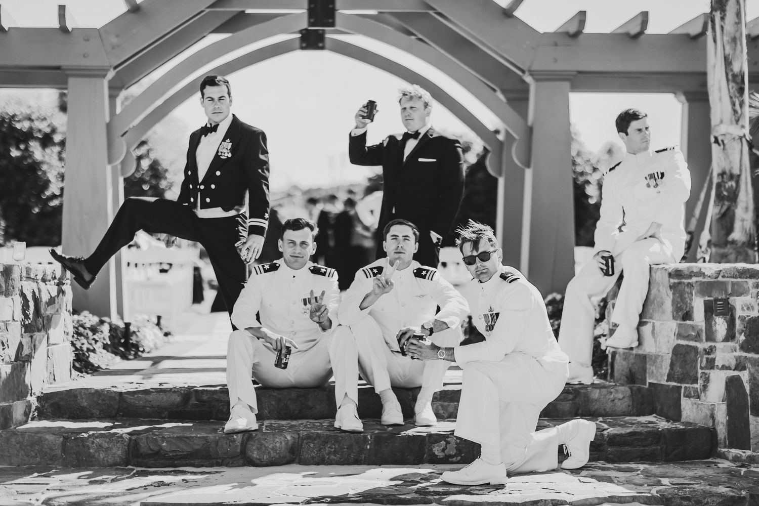 A vintage black and white photograph showing a group of young men in white outfits gathered on outdoor steps.