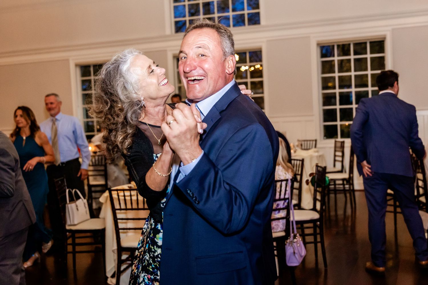 Wedding guests share a joyful moment dancing together at an indoor reception.