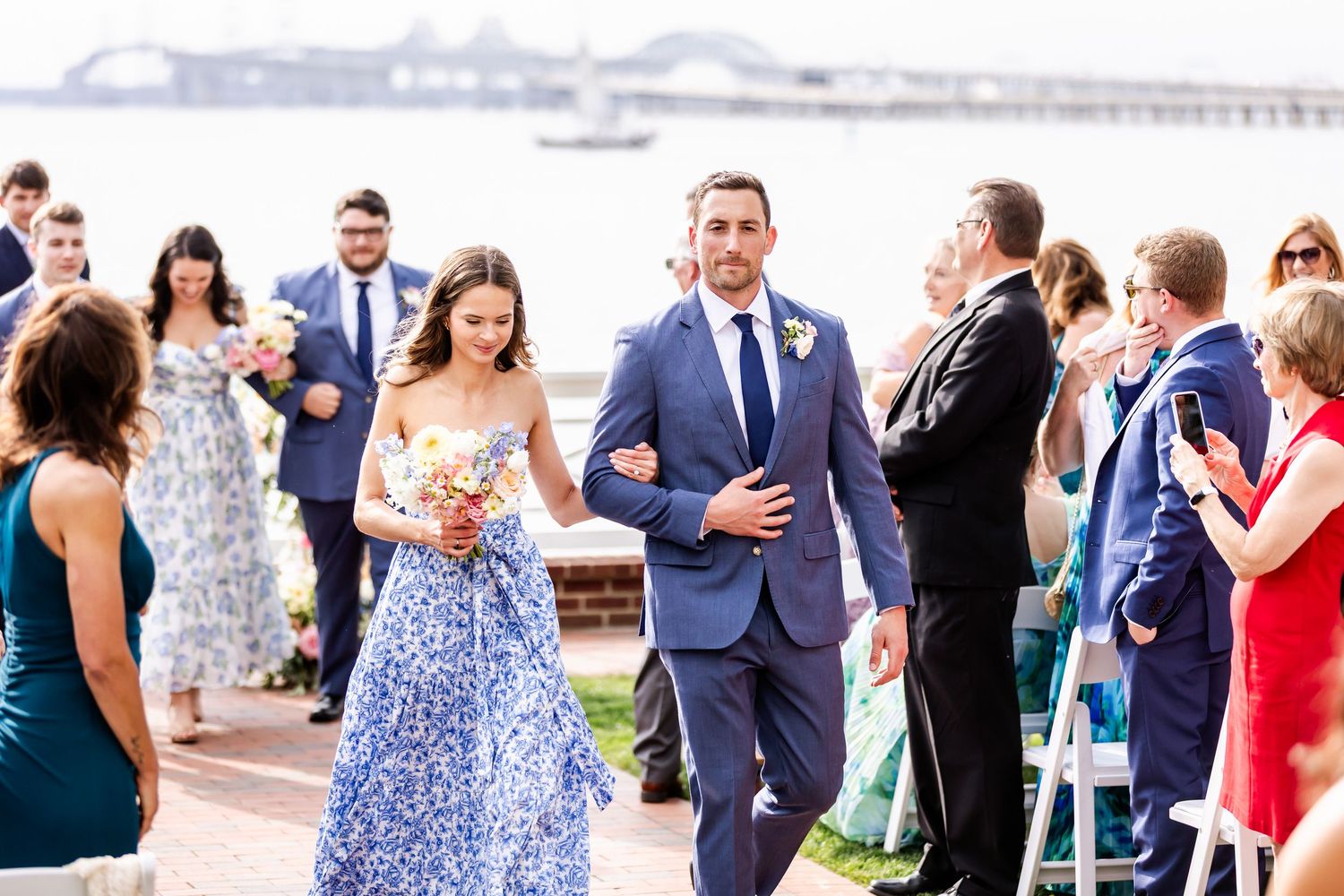 Wedding guests socializing at an outdoor reception with water views.