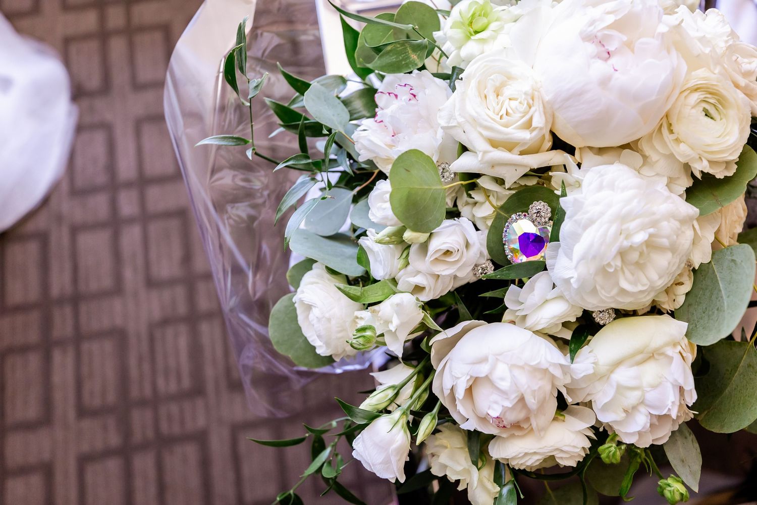 Close-up of a white rose wedding bouquet with delicate greenery and purple accents.
