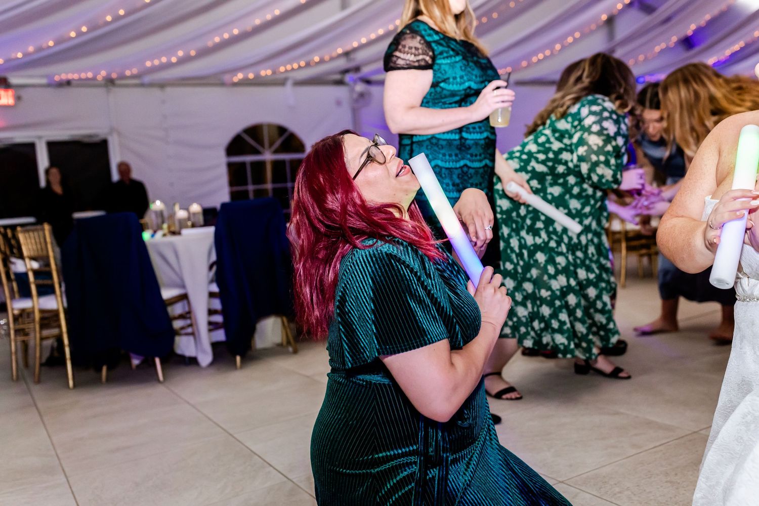 Wedding guests dancing and celebrating in elegant evening attire under draped fabric ceiling.