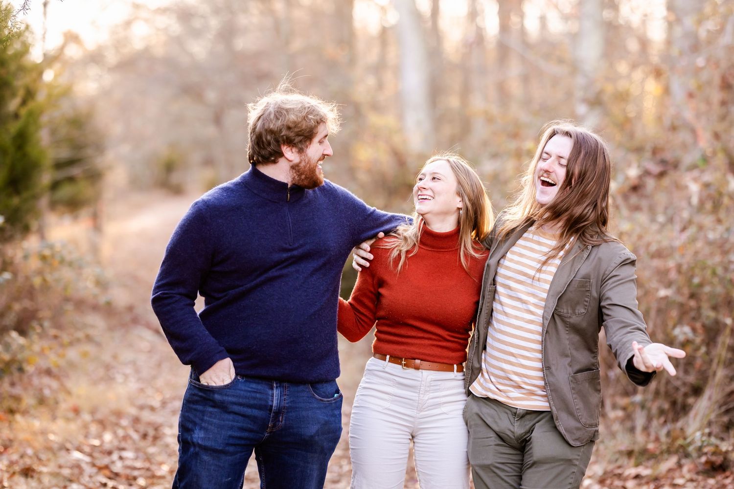 A group of three people sharing genuine laughter while walking outdoors in autumn.