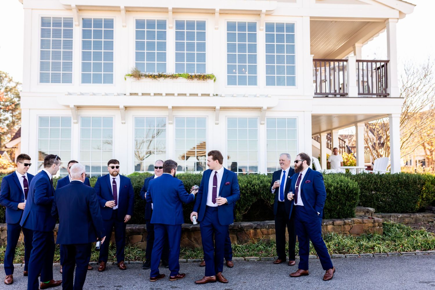 Group wearing navy suits gathered outside a two-story white house with large windows.